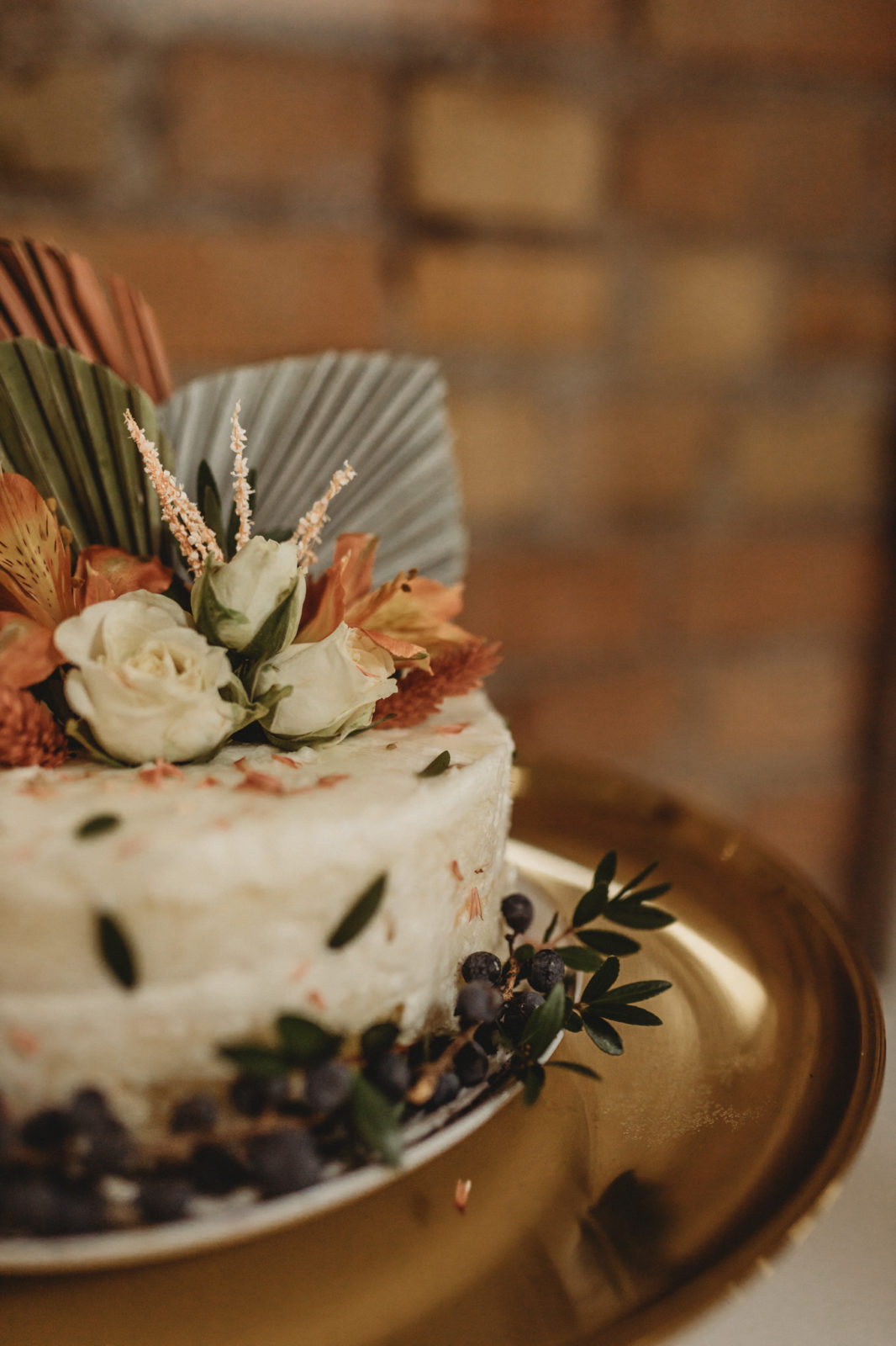 Modern white wedding cake topped with sage and orange florals