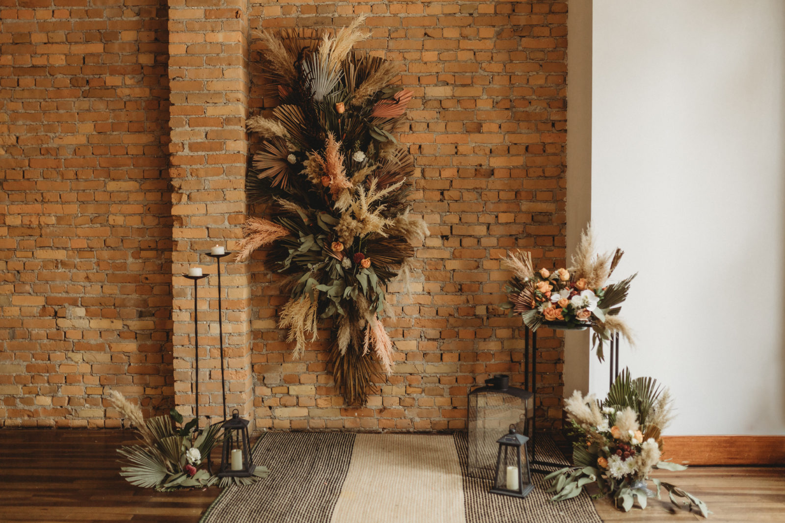 Boho wedding ceremony decor styled by Chemistry Events featuring dried florals and a brick wall at The Garret