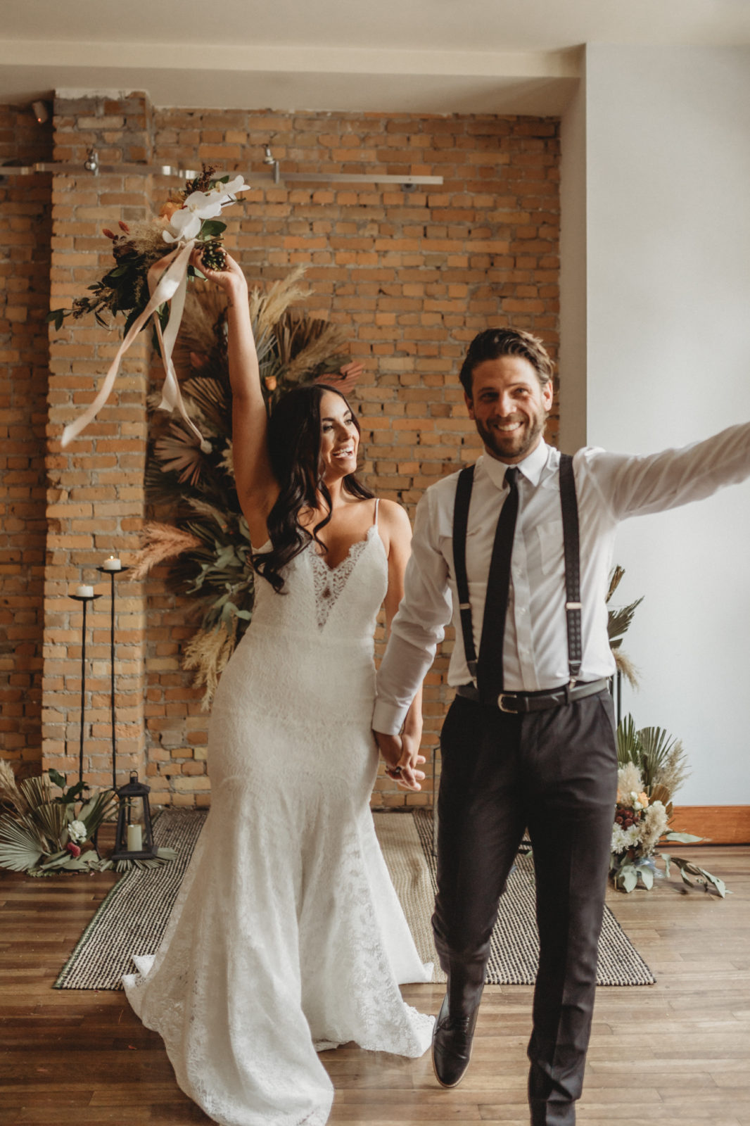 Bride and groom celebrate in front of their dried floral ceremony decor styled by Chemistry Events