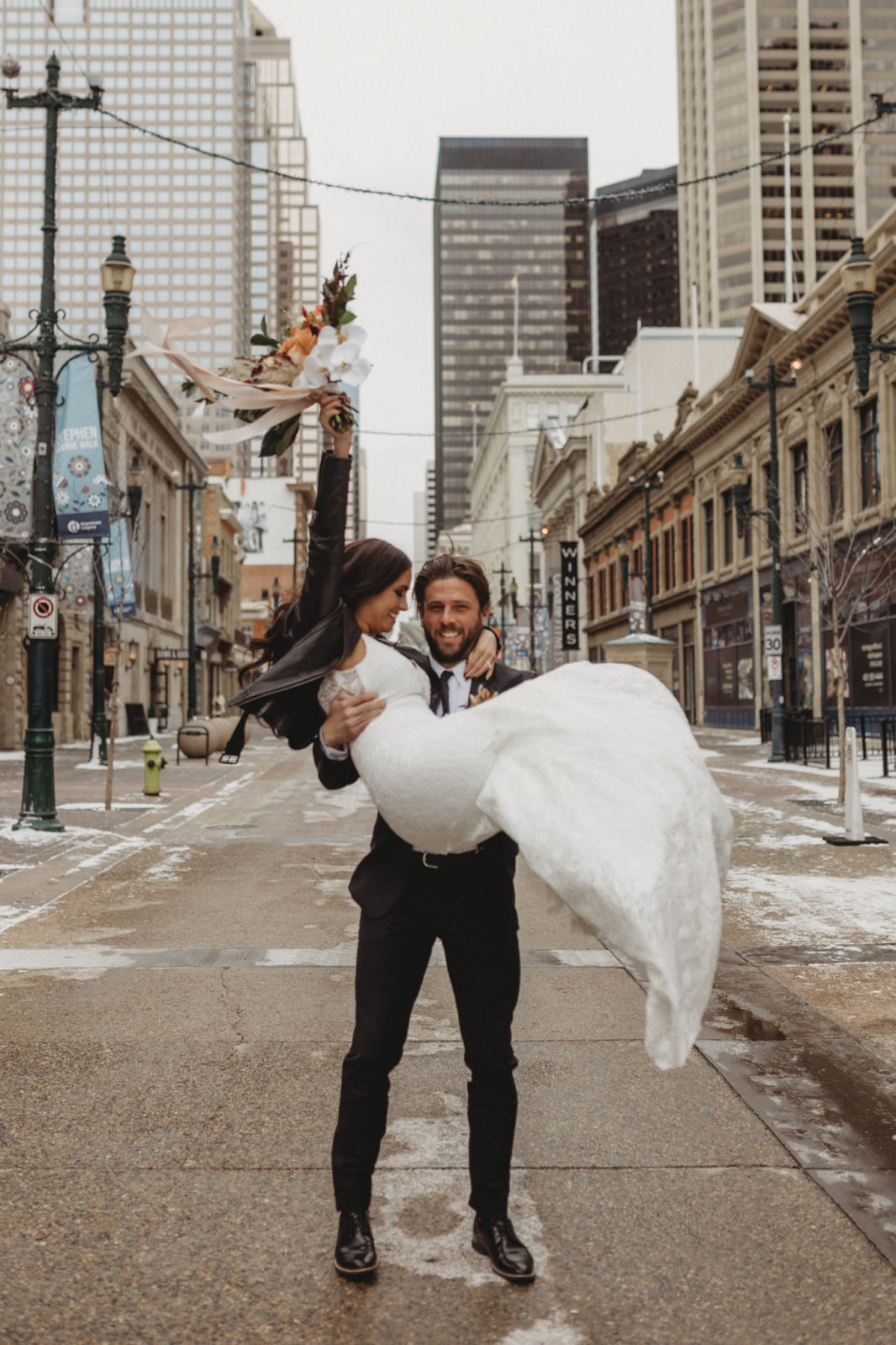 Groom pick up his leather jacket wearing bride in the streets of downtown Calgary