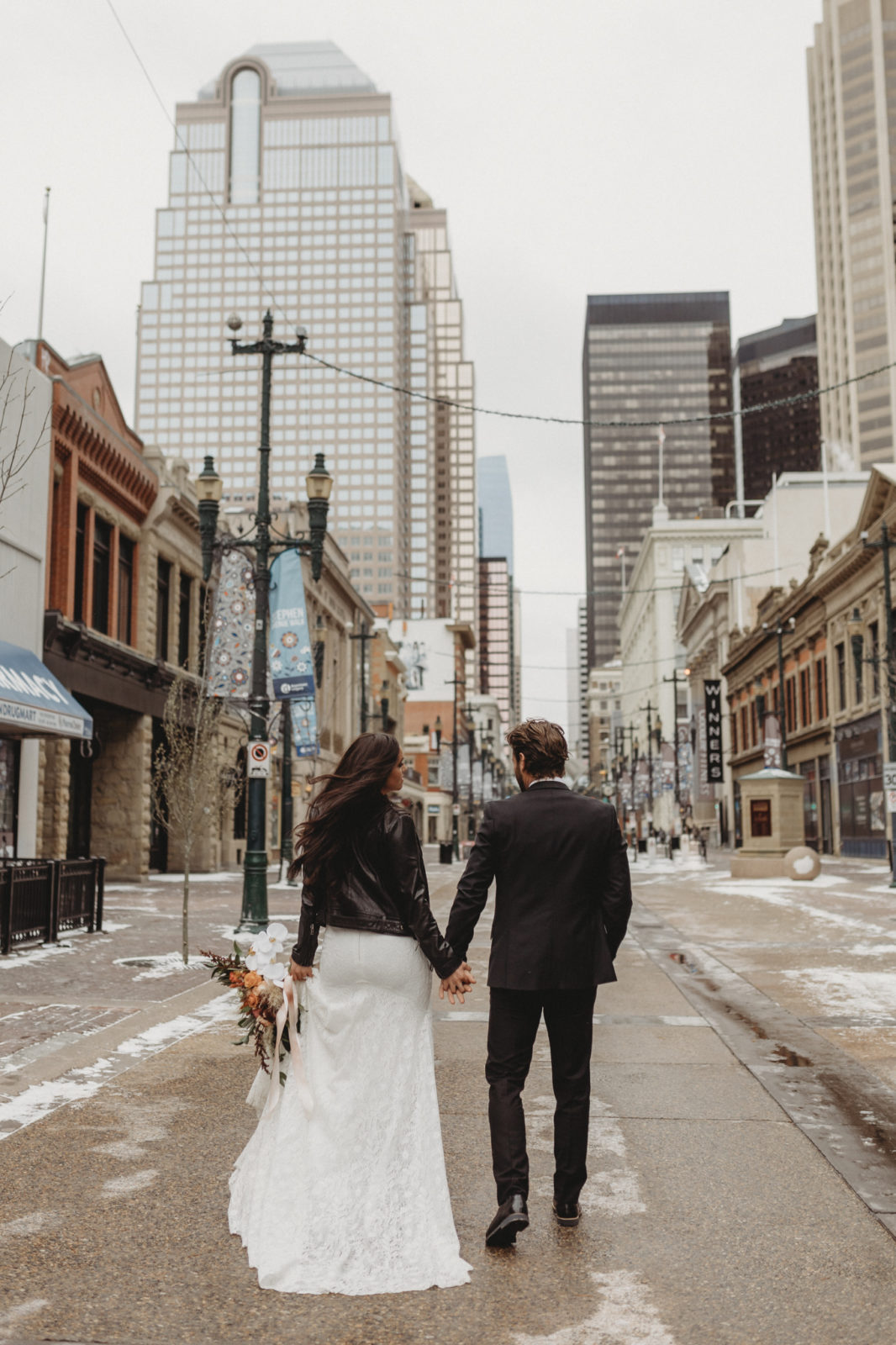 Modern bride and groom stroll through downtown Calgary on their wedding day
