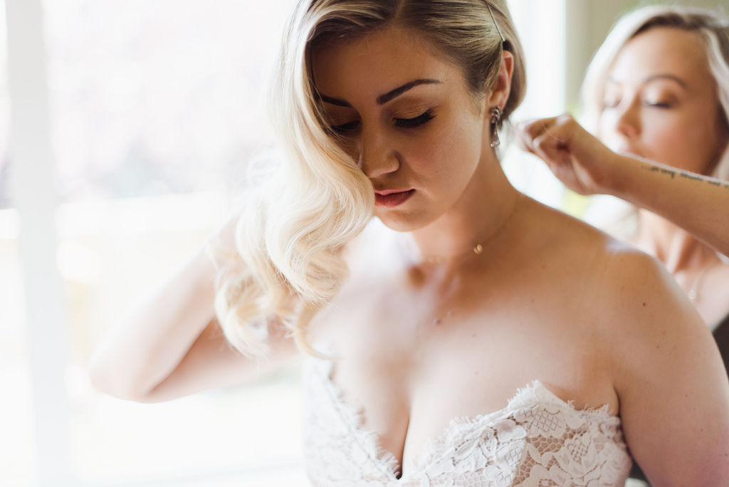 Bride poses in front of a window on the morning of her whimsical wildflower wedding