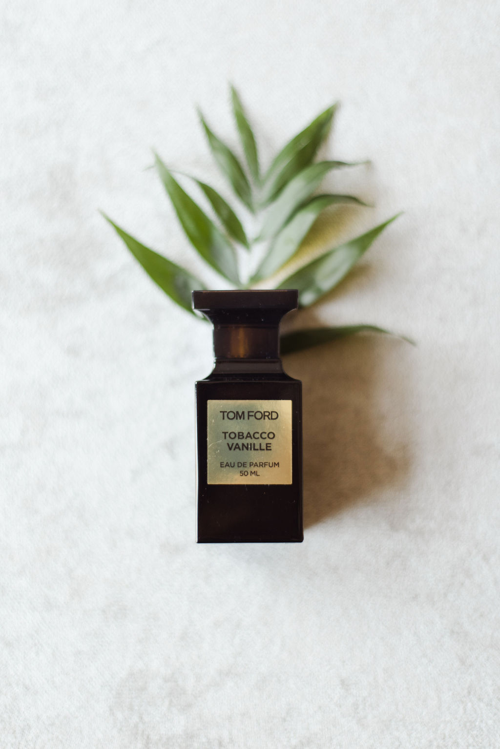 Tom Ford Tobacco photographed with greenery against a white marble backdrop