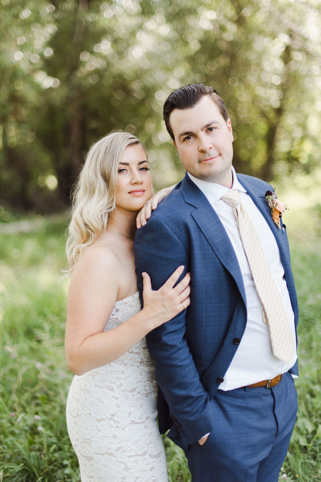 Calgary bride poses while holding onto her groom's arm and shoulder