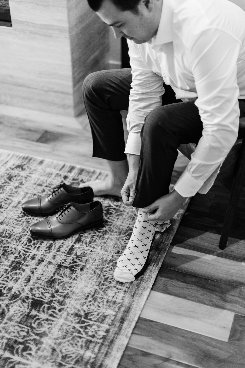 Calgary groom is photographed putting on shoes and socks in preparation for his wedding day