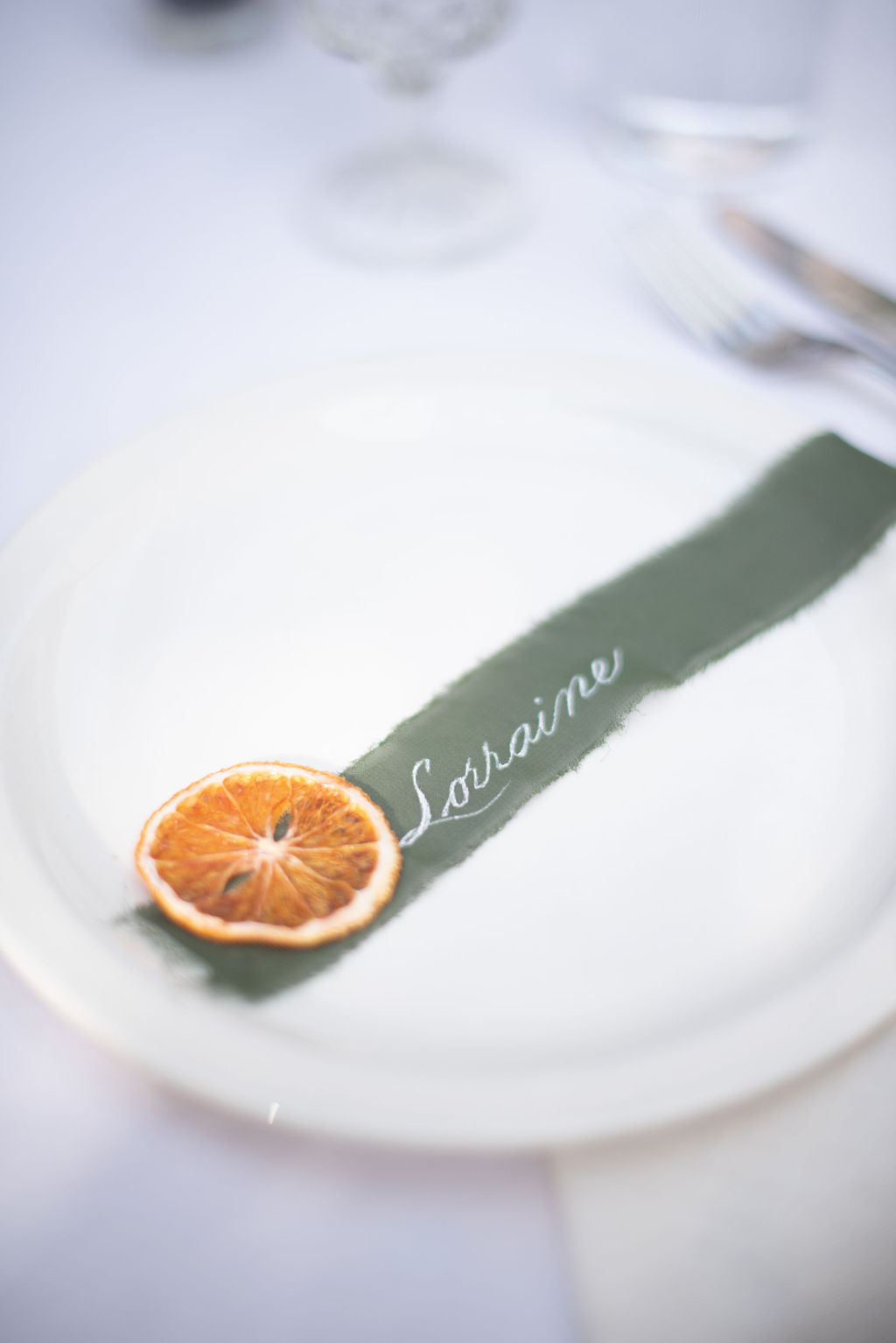 Wedding place settings created with orange slices and olive ribbon