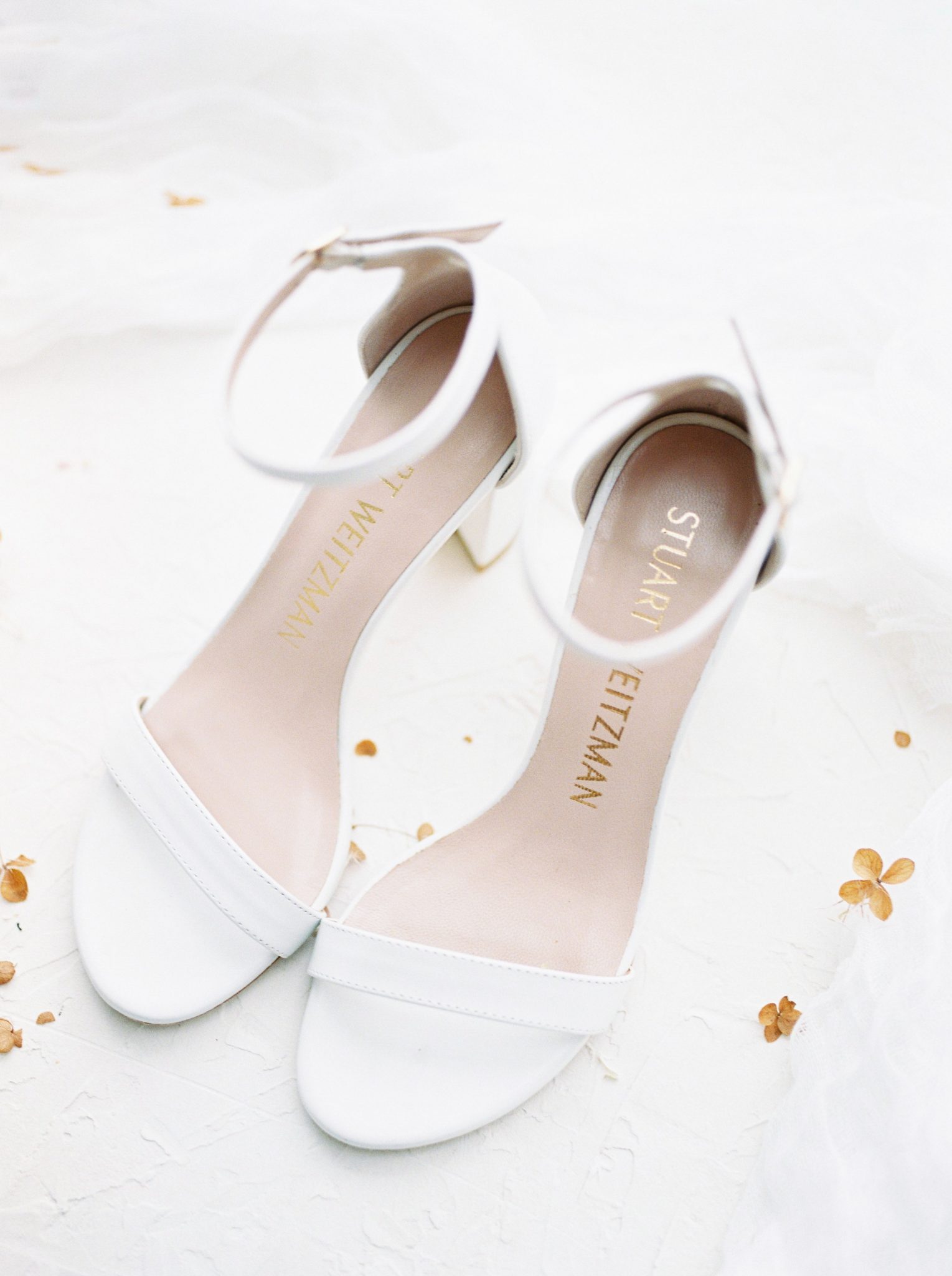 White Stuart Weitzman heels styled in front of a white backdrop for a modern Okanagan wedding ceremony