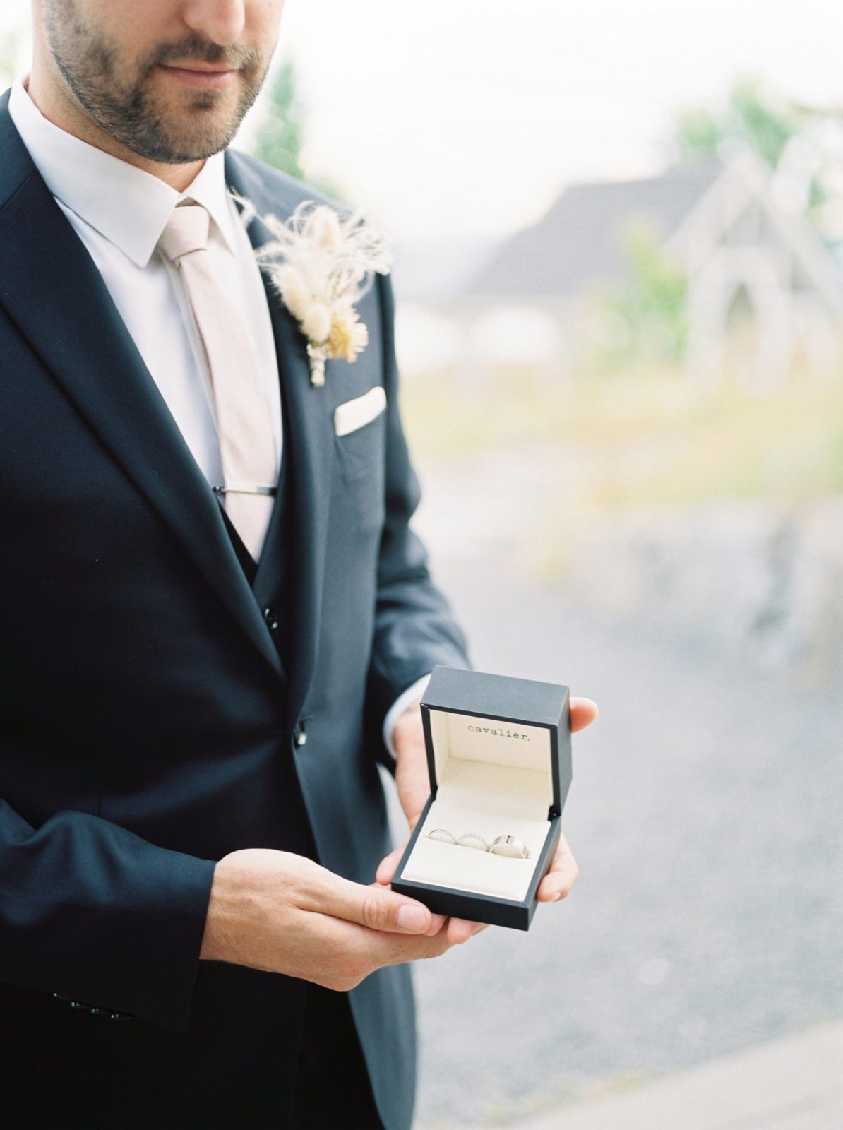 Groom holds box containing wedding bands