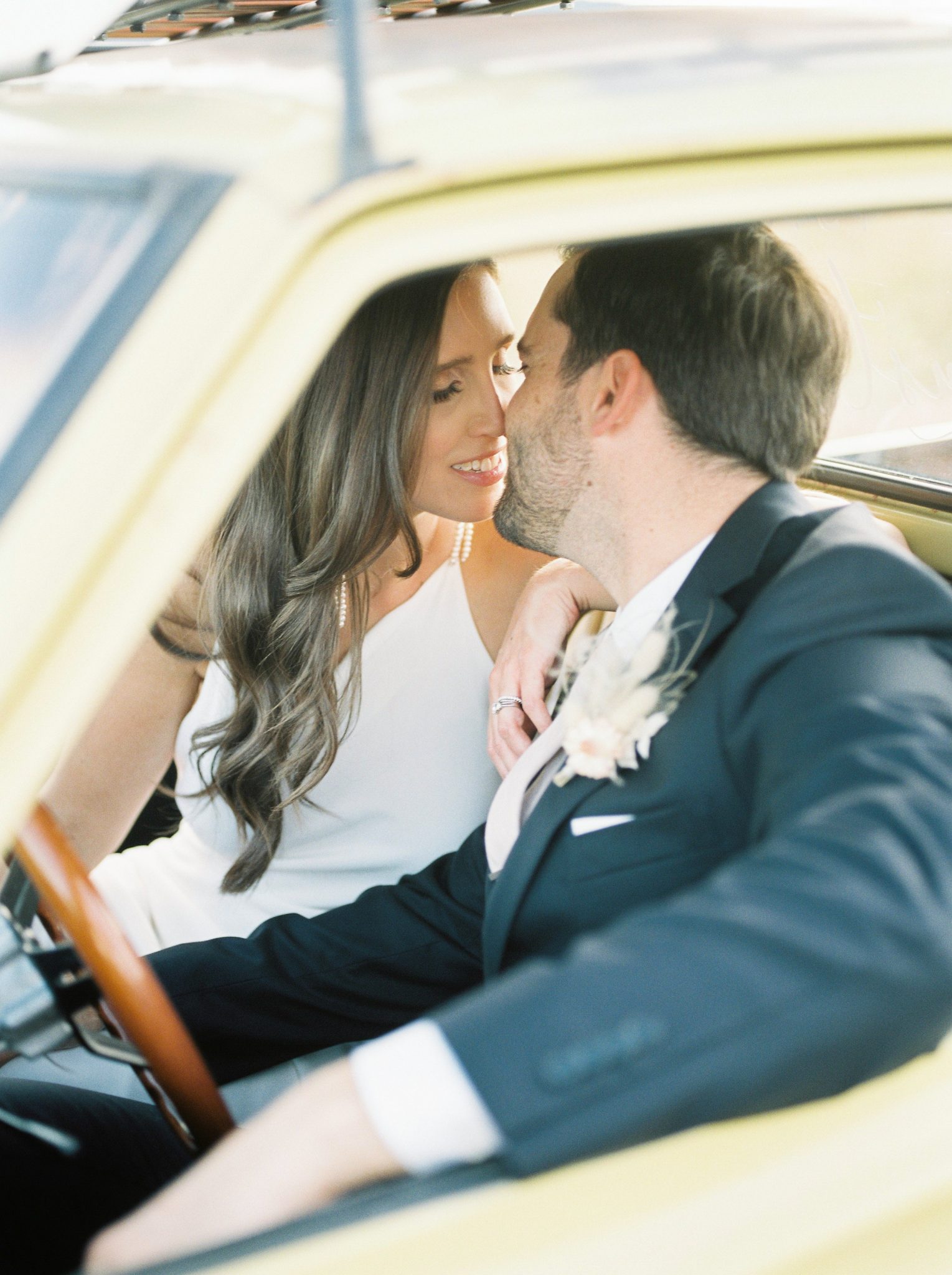 Bride and groom share a kiss from inside their yellow pickup truck