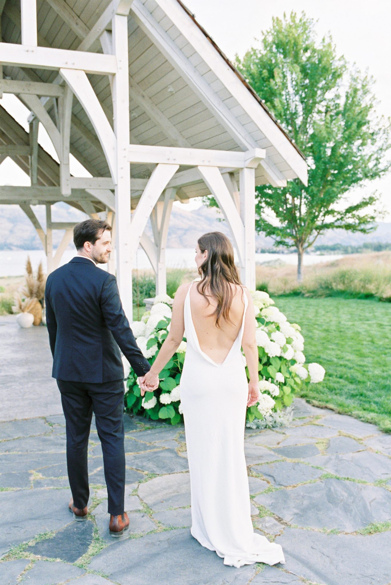 Modern bride and groom walk towards the chapel inspired gazebo at Sanctuary Gardens in Okanagan British Columbia