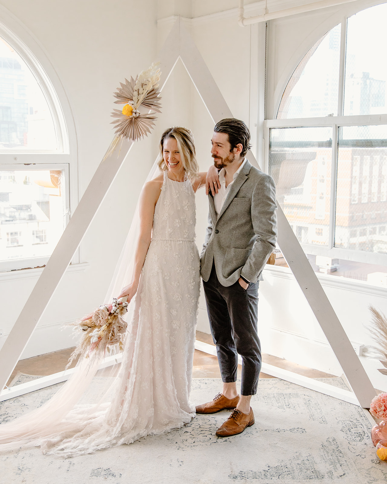 Bride and groom pose in front of a modern ceremony arch for their Gastown elopement in Vancouver