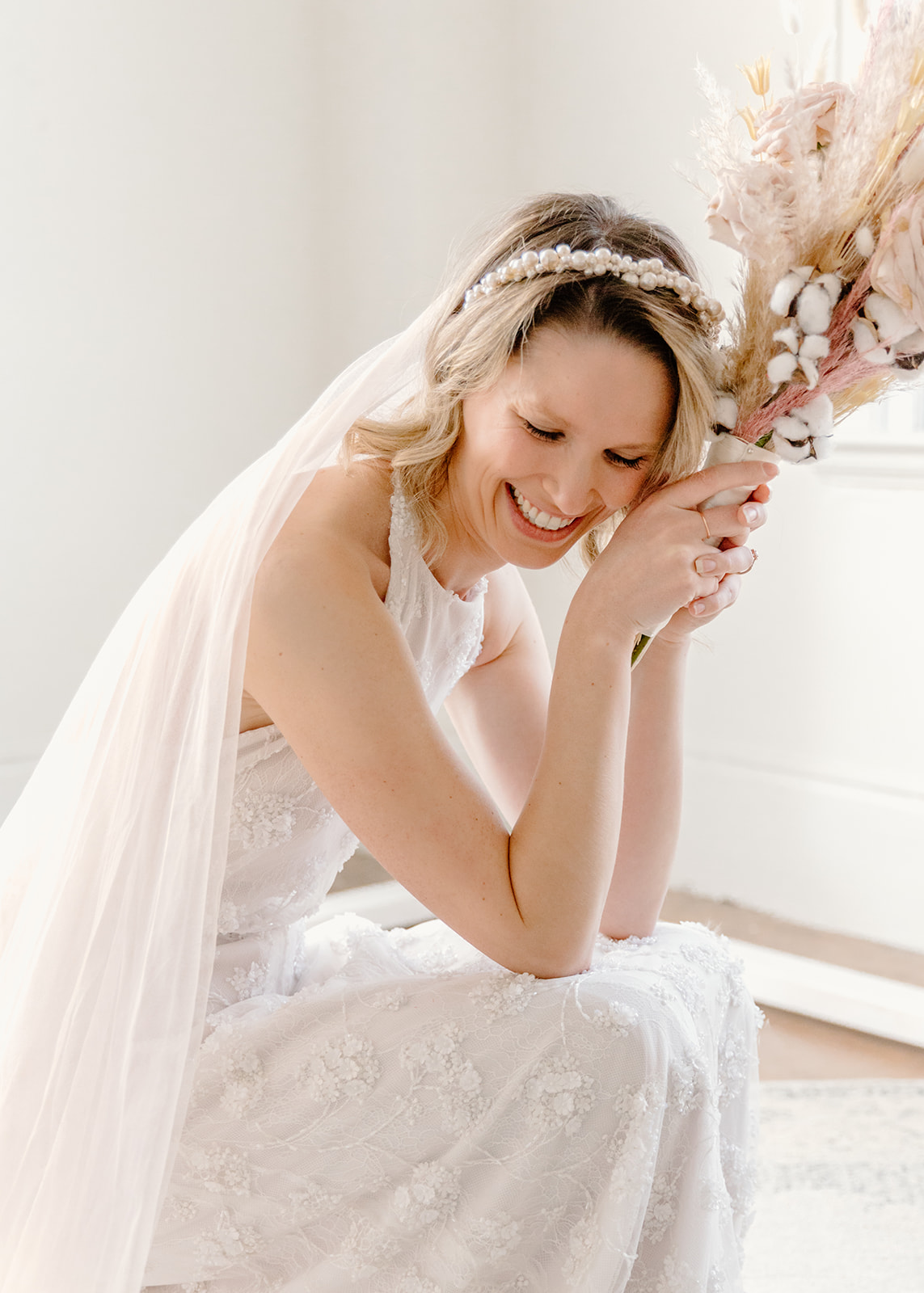 Bride with a pearl headband poses with a dried floral bouquet