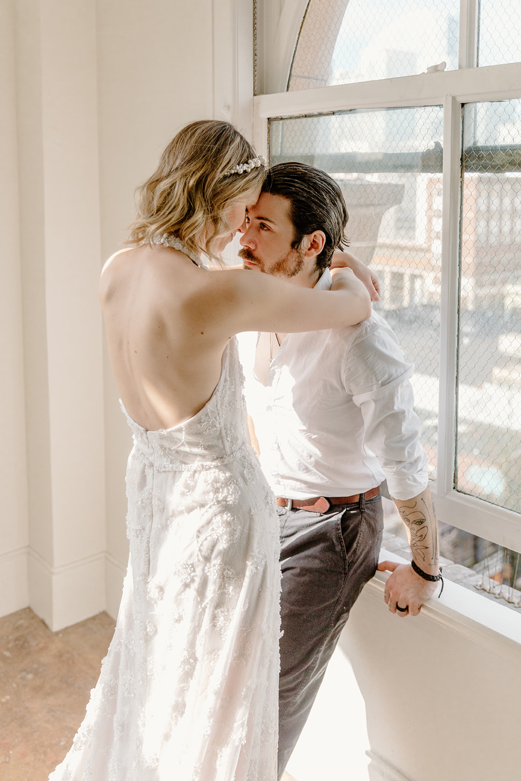 Eloping bride and groom pose in front of a window sill in Gastown Vancouver