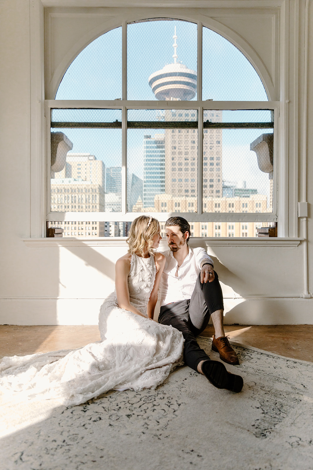 Bride and groom pose in front of a sunny window sill in Gastown Vancouver for their urban elopement