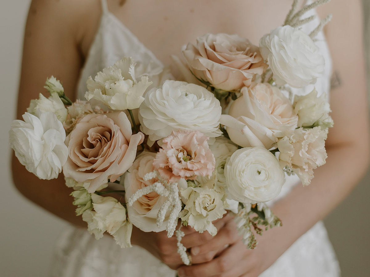 Blush wedding bouquet featuring quicksand roses, ranunculus, lisianthus, japanese pieris