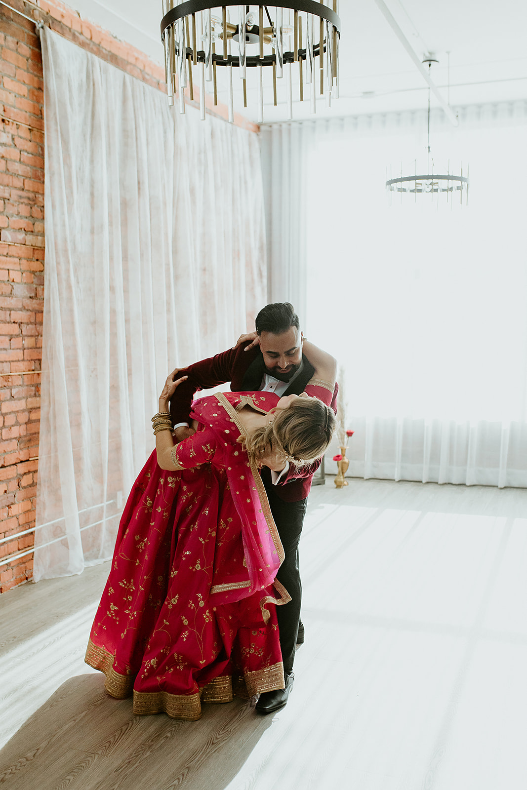 Bride in a bright pink lehenga and groom share their first dance at Venue 308 in Calgary Alberta
