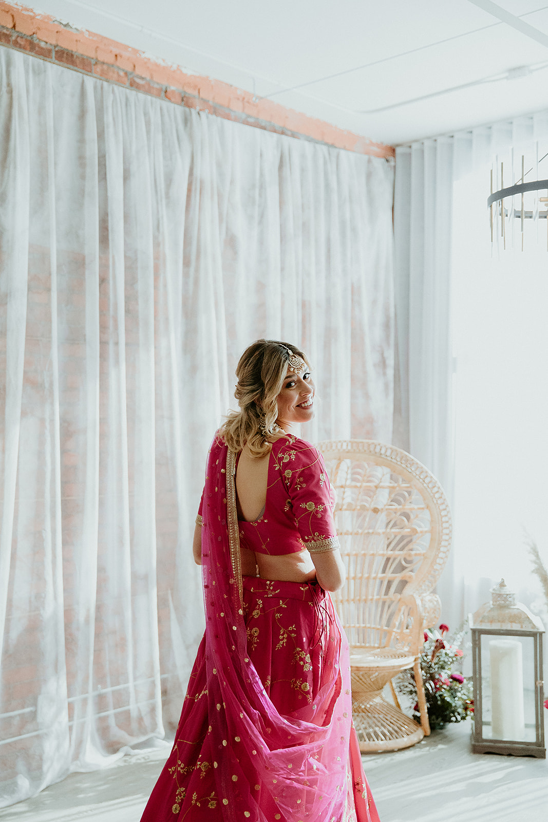 Bride in a bright pink lehenga poses at Venune 308 on her wedding day inspired by Indian and Moroccan vibes