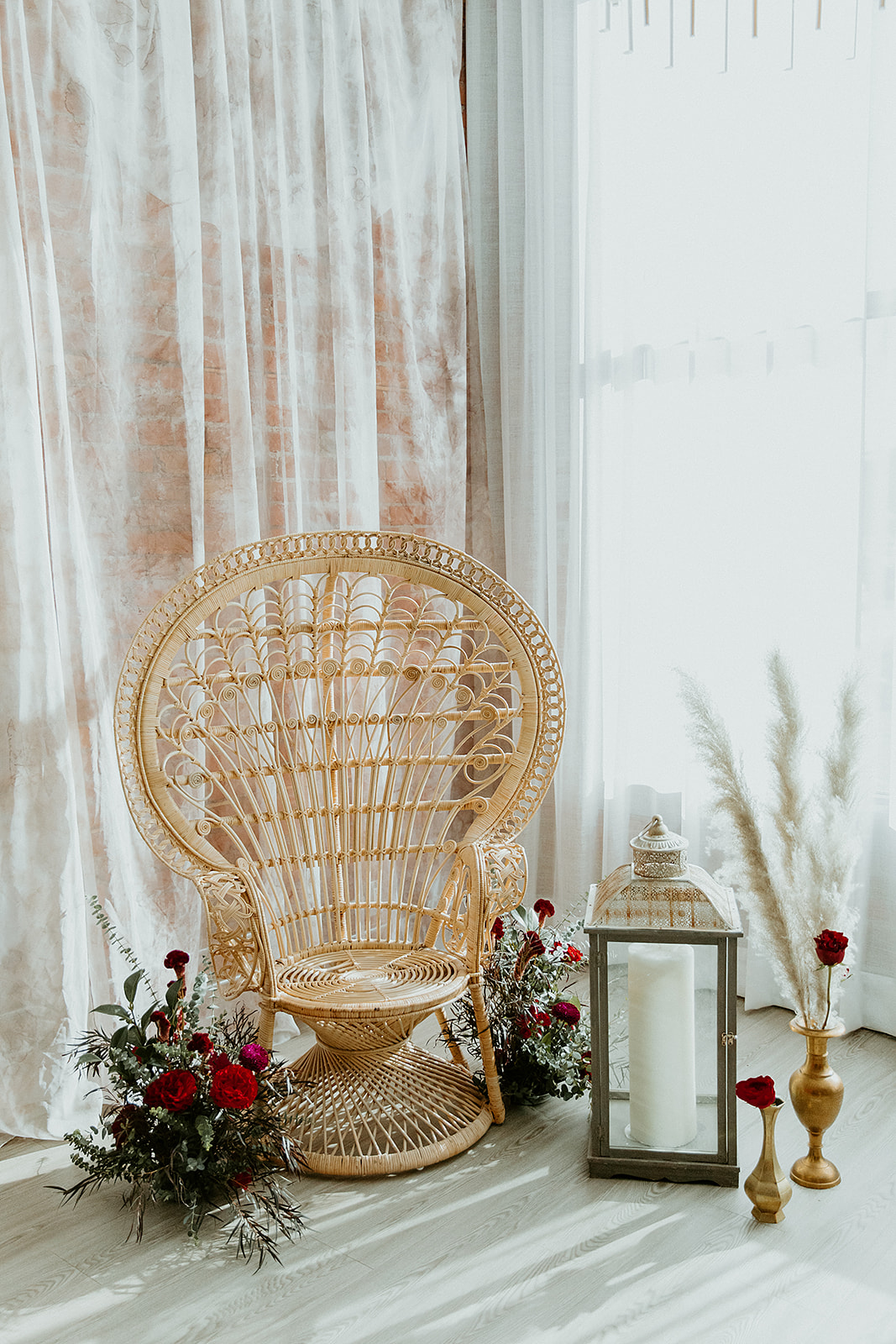 Indian and Moroccan inspired wedding ceremony decor with an ornate rattan chair and wild pampas grass