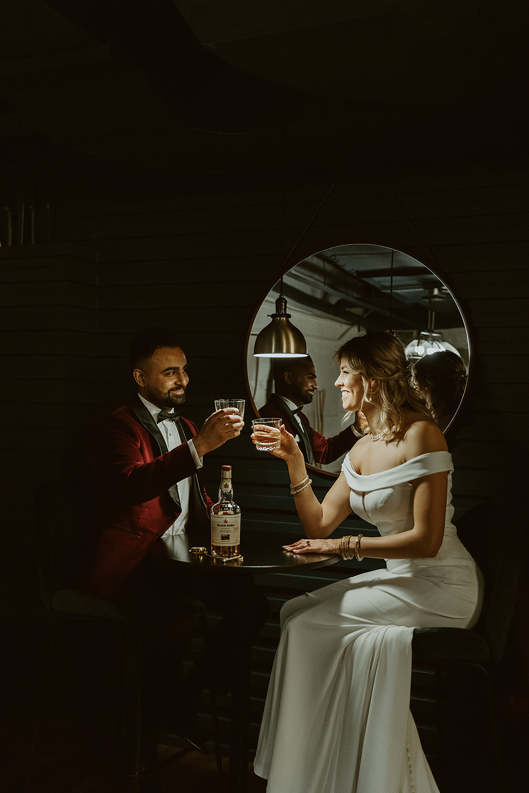 Bride and groom share a drink on their wedding day in the chic and moody basement of Venue 308 
