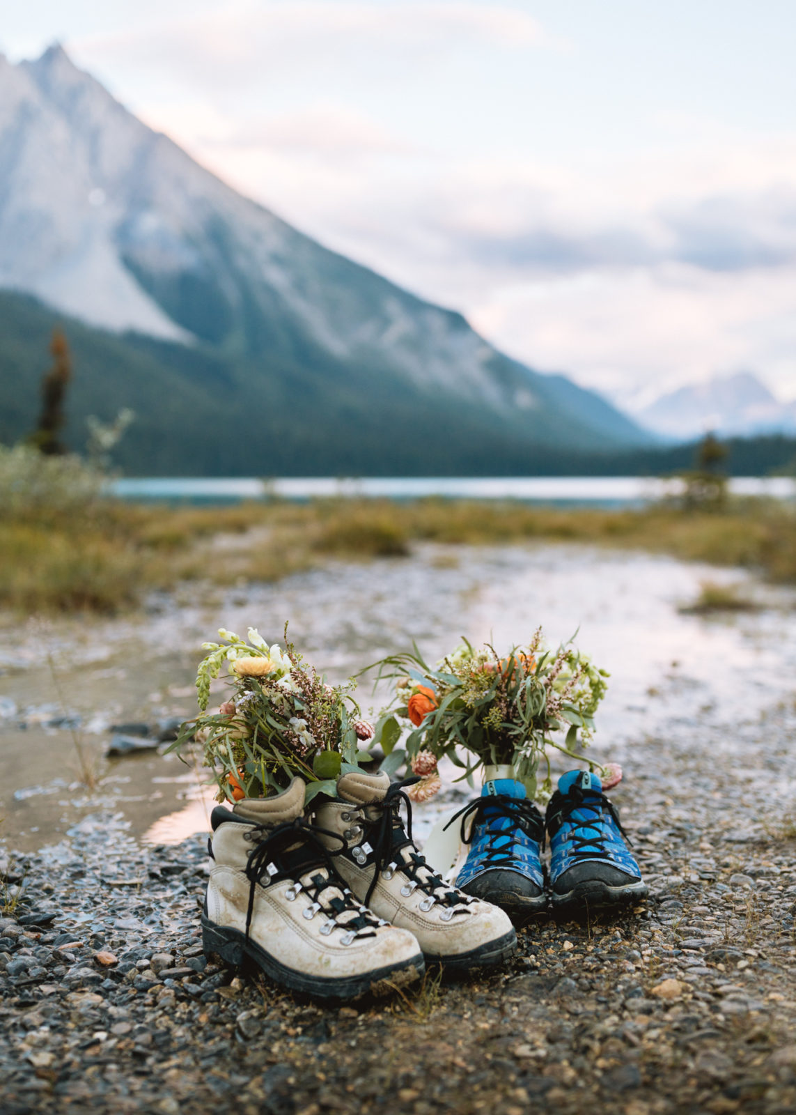 Wedding bouquets featuring pops of orange photographed with hiking boots in front of mountains in Yoho National Park