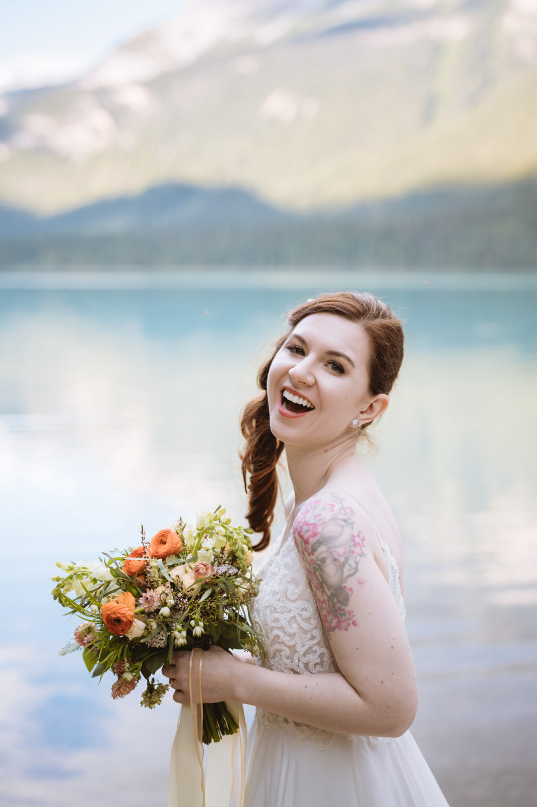 Bride strikes a playful pose with Emerald Lake in the background for her Elopement in Yoho National Park