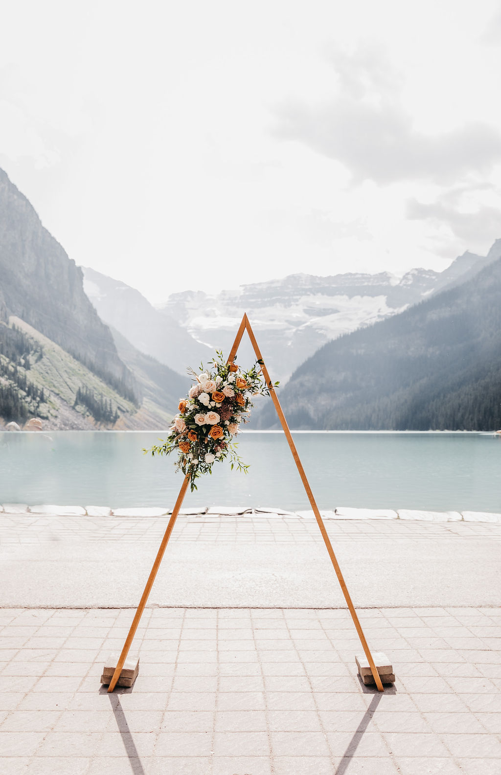 Triangle wedding ceremony arch adorned with roses at Lake Louise