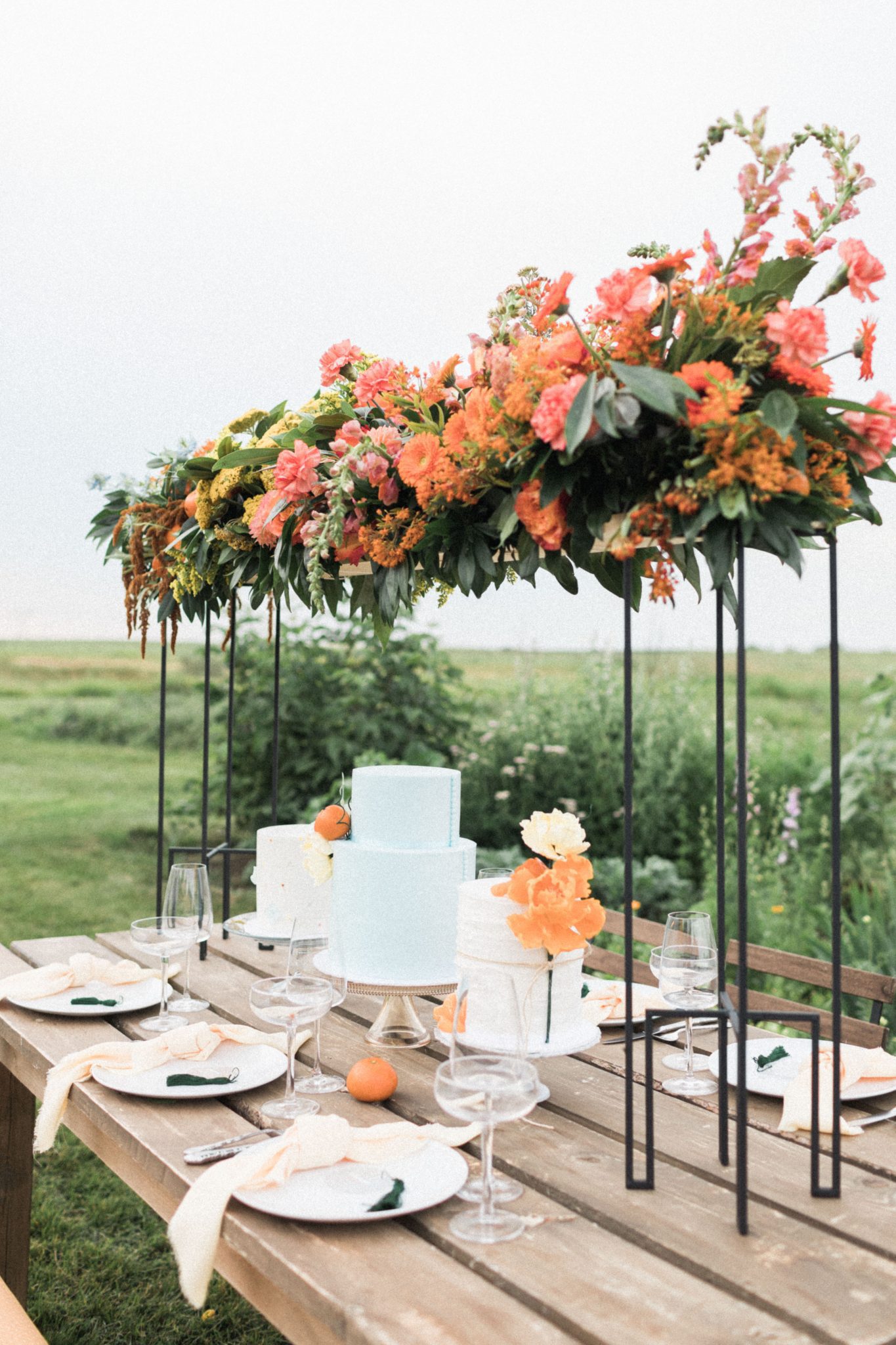 Floral arch and robin blue wedding cake on a farm table for a countryside garden wedding
