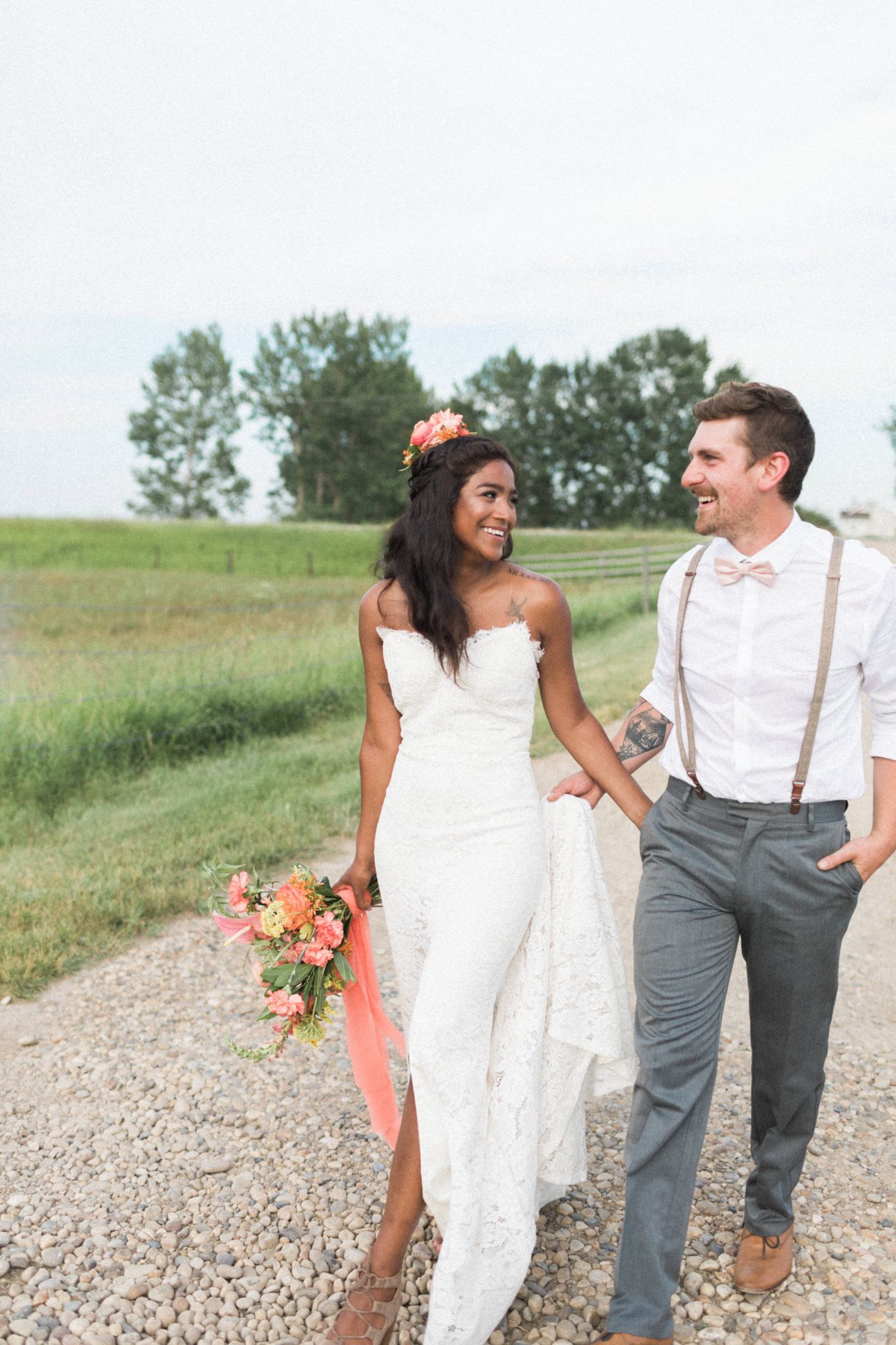 Bride and groom walk down a country road on their wedding day with pink and tangerine flowers