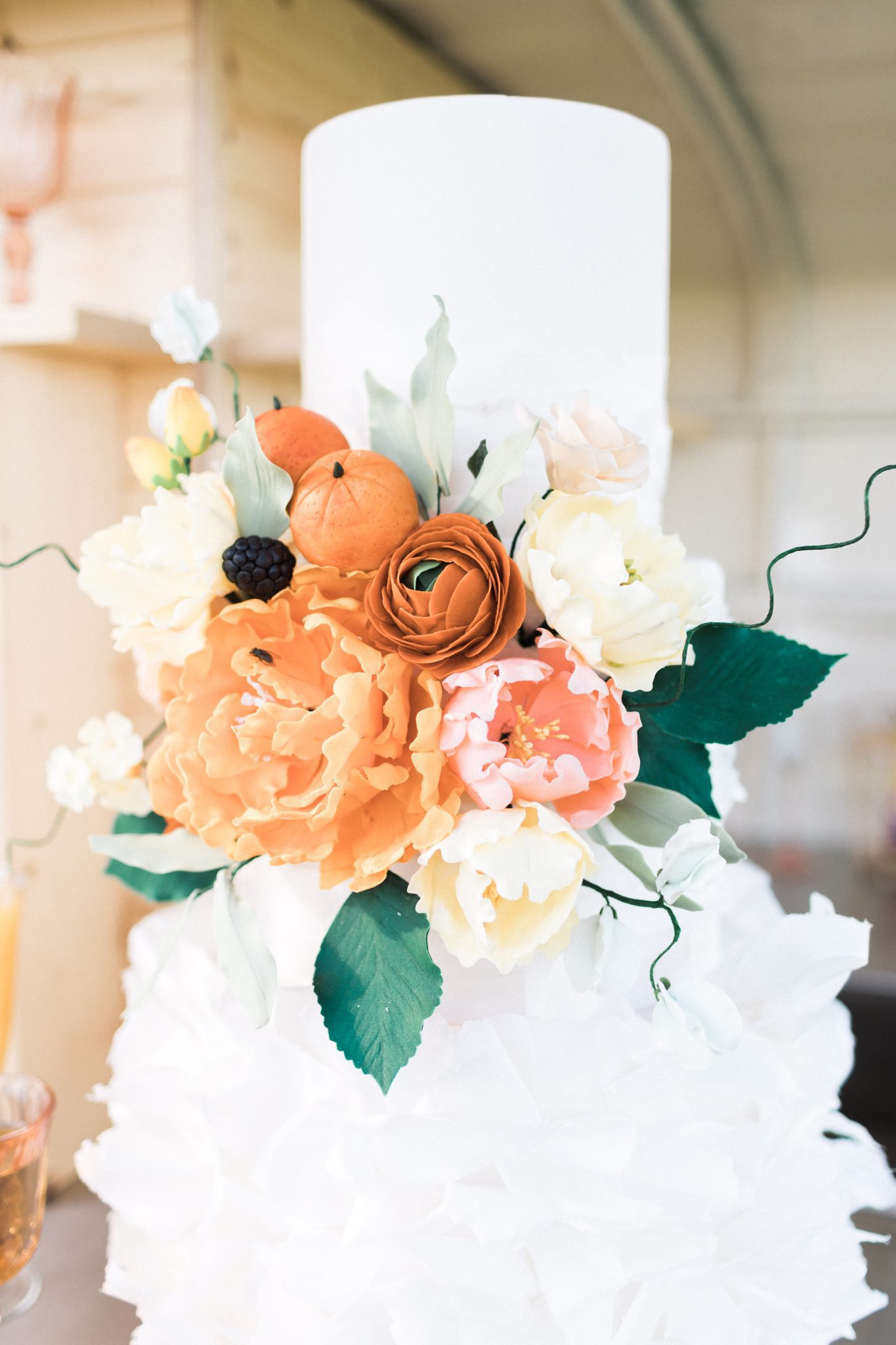 White ruffled cake with tangerine and floral accents