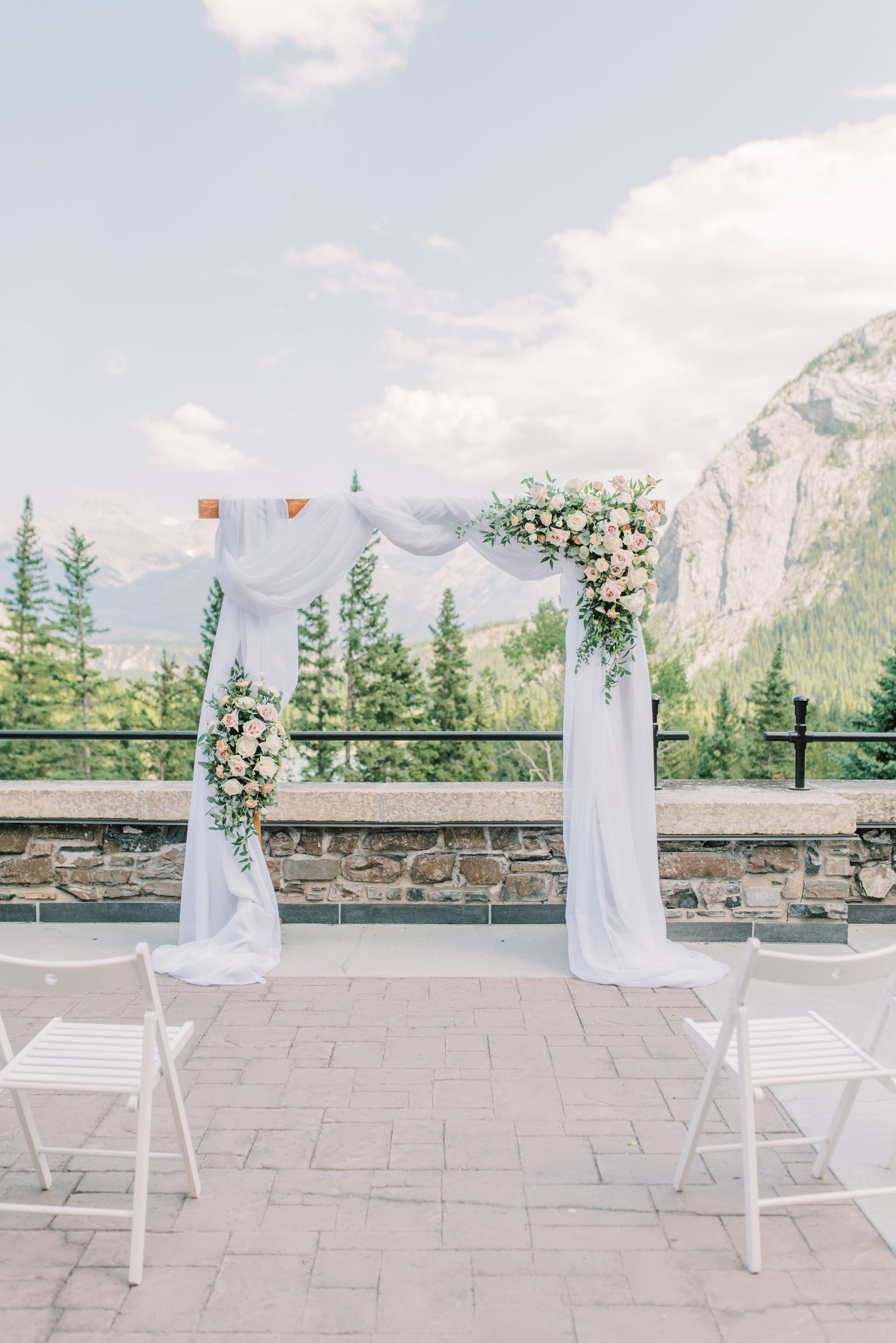 Traditional wedding ceremony arch adorned with pink and white roses at the Fairmont Banff Springs Hotel