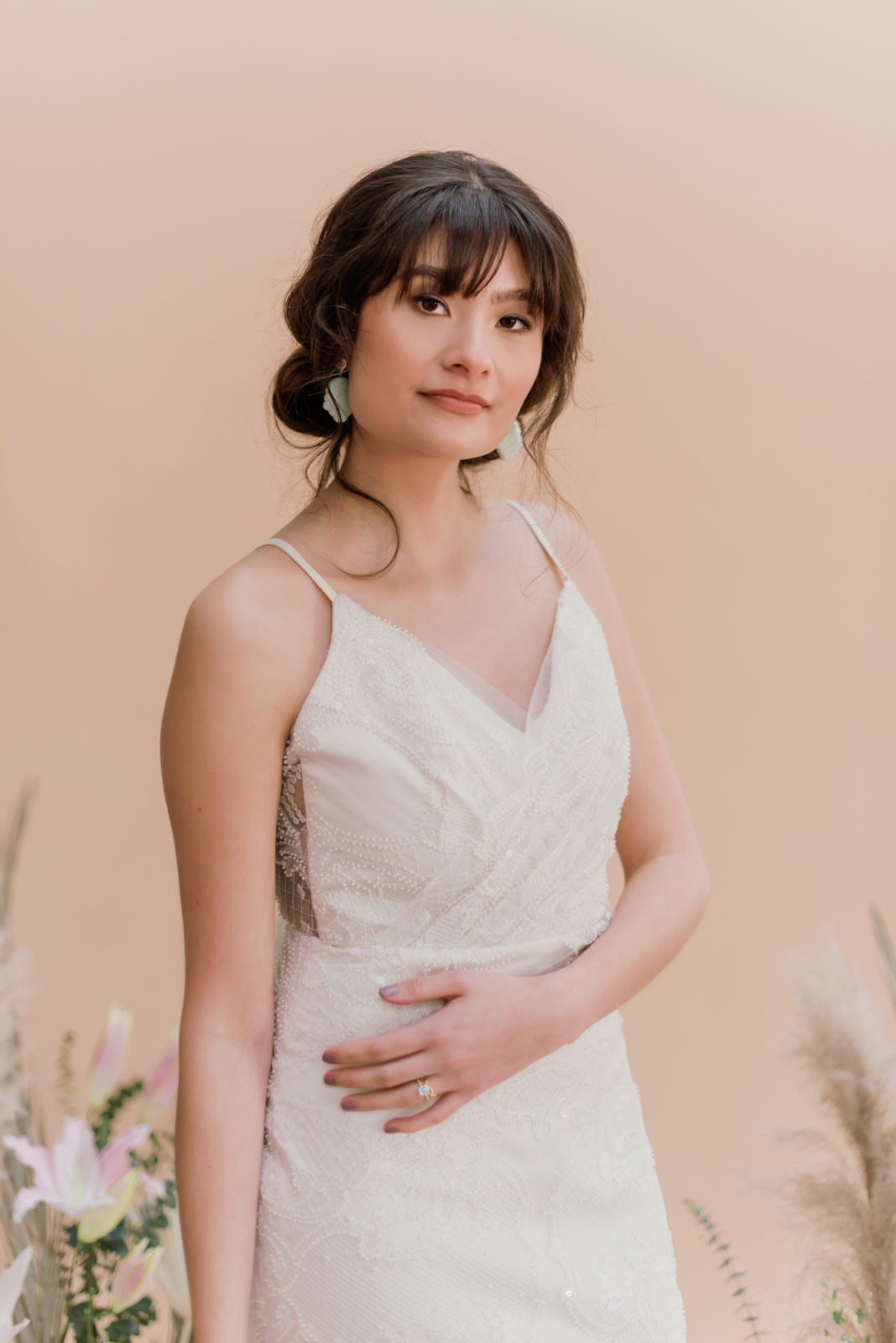 Bridal model poses in the Bree wedding dress by Laudae, a full beaded wedding gown