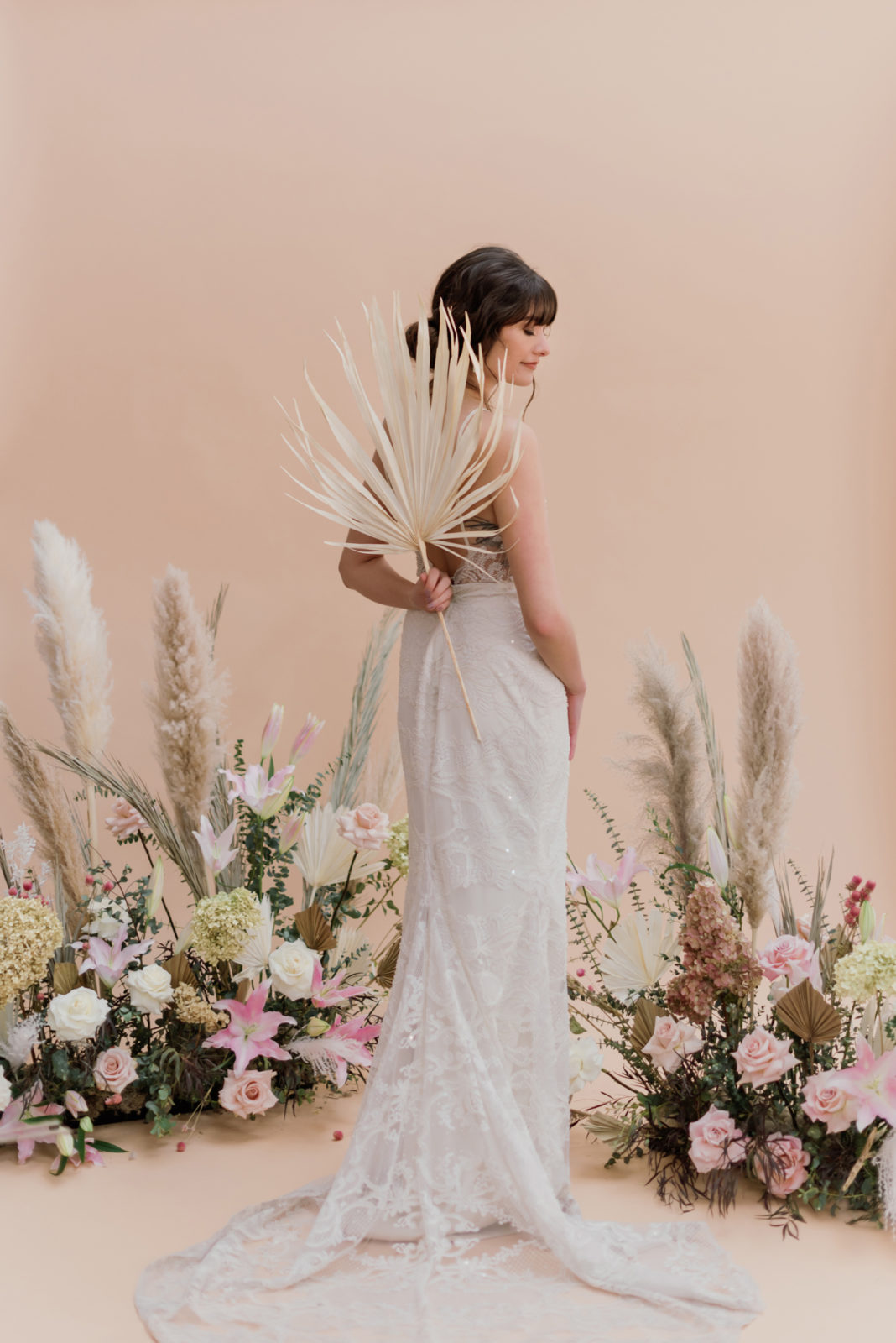 Model poses holding a palm frond behind her back for this renaissance inspired bridal editorial