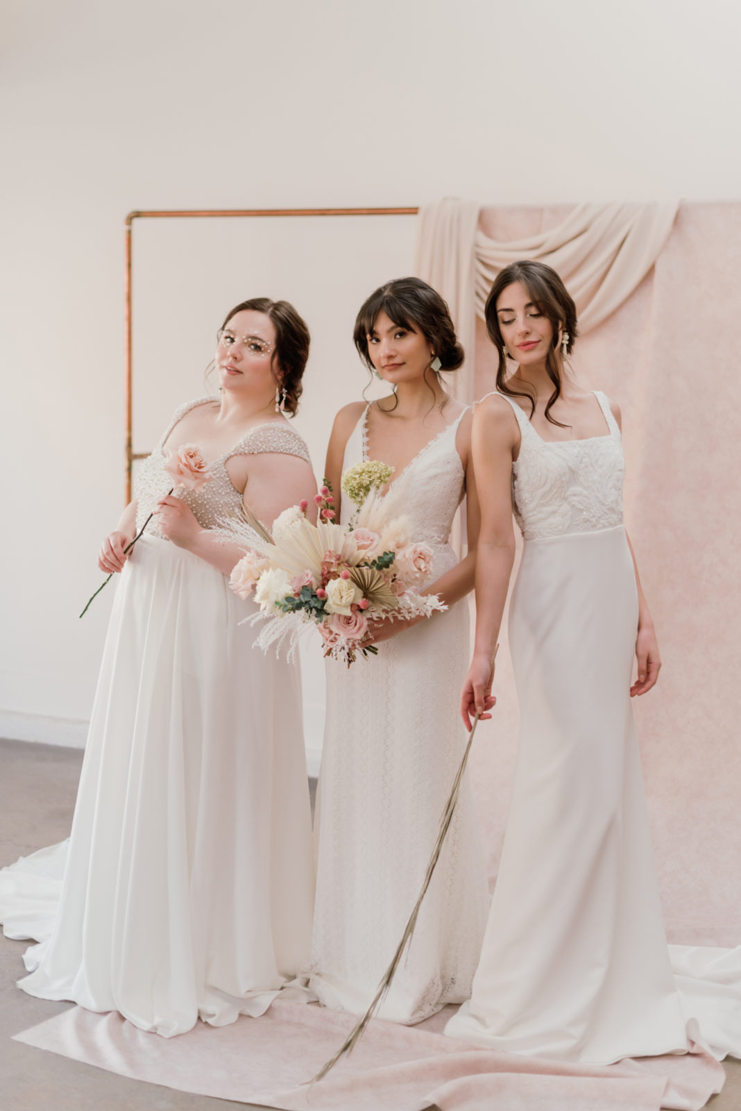 Three models pose in front of a renaissance inspired backdrop wearing wedding dresses from Lovenote Bride's newest collection