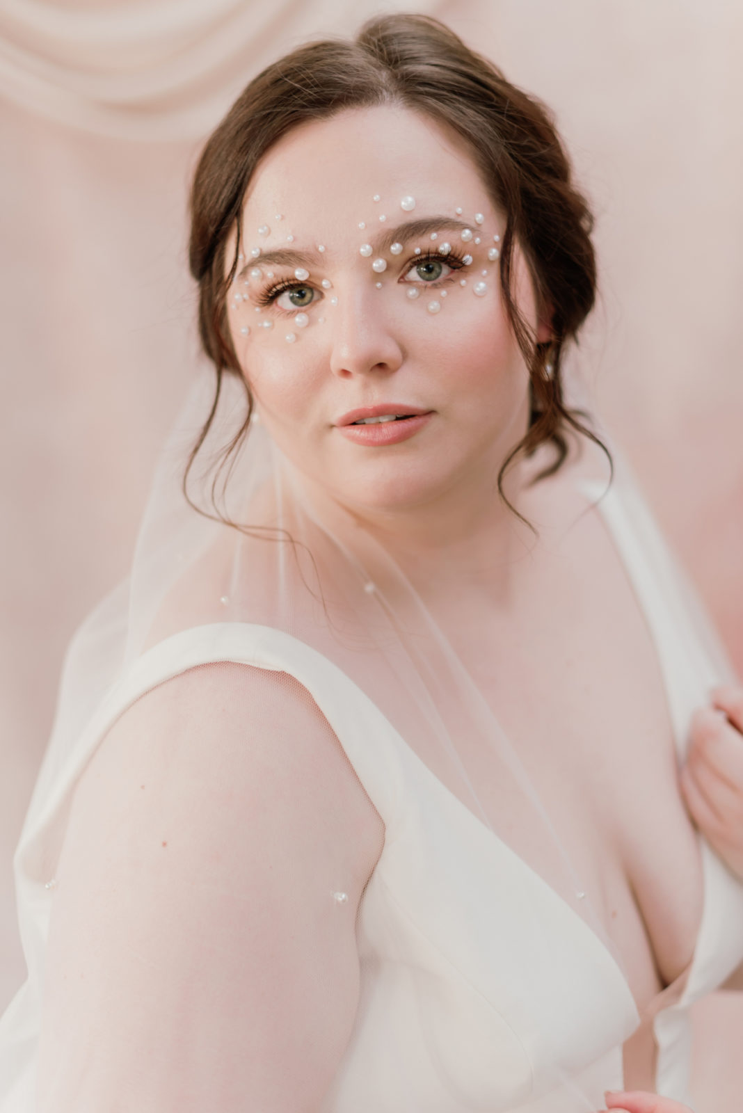 Model with romantic pearl studded eye makeup poses in the Selcouth wedding gown by Aesling