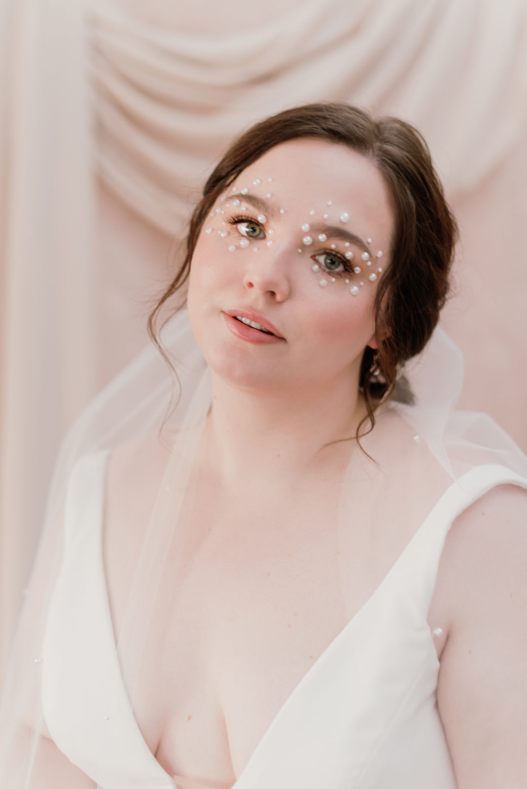 Model with pearls for eye makeup poses in the selcouth wedding dress by Aesling