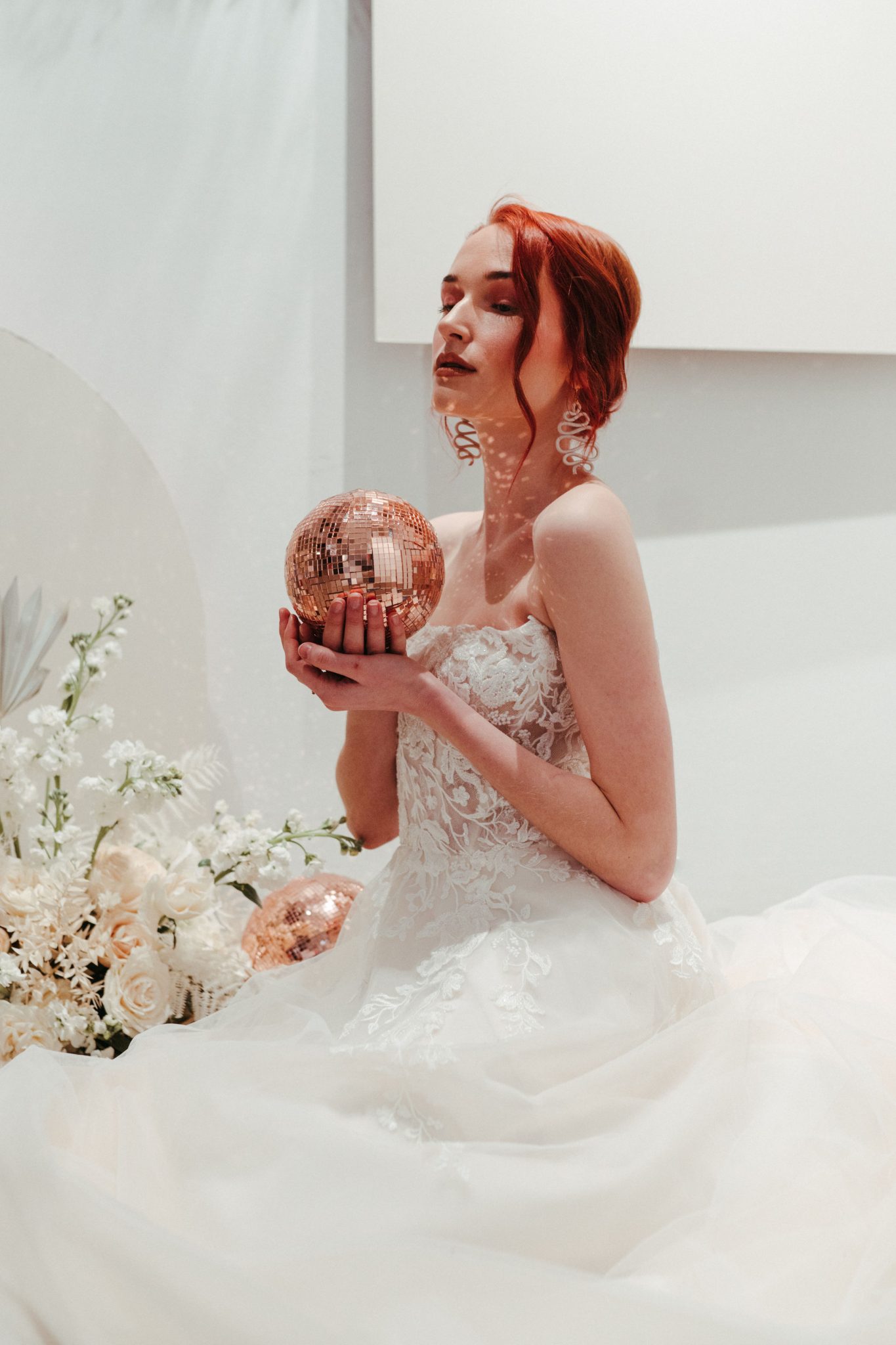 Red head bride poses with a rose gold disco ball 