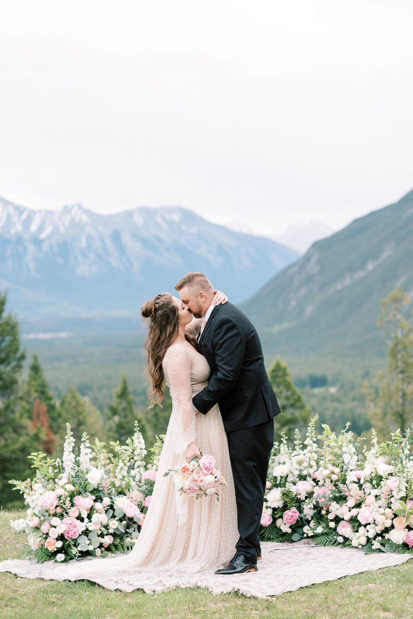 Newly eloped bride and groom share a kiss with the mountains of Banff National Park in the background