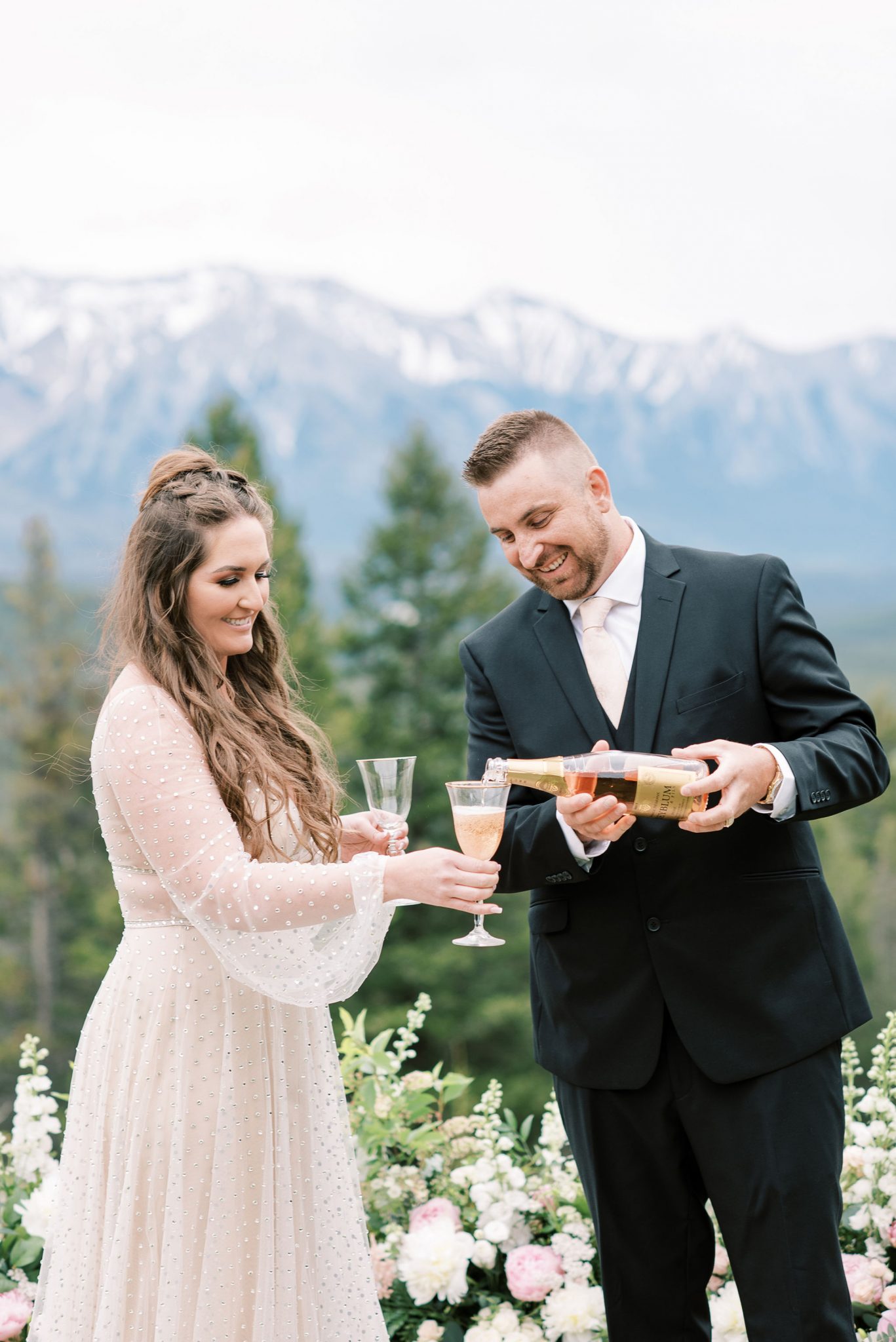 Groom pours champagne into his bride's champagne flute for their elopement at Banff National Park