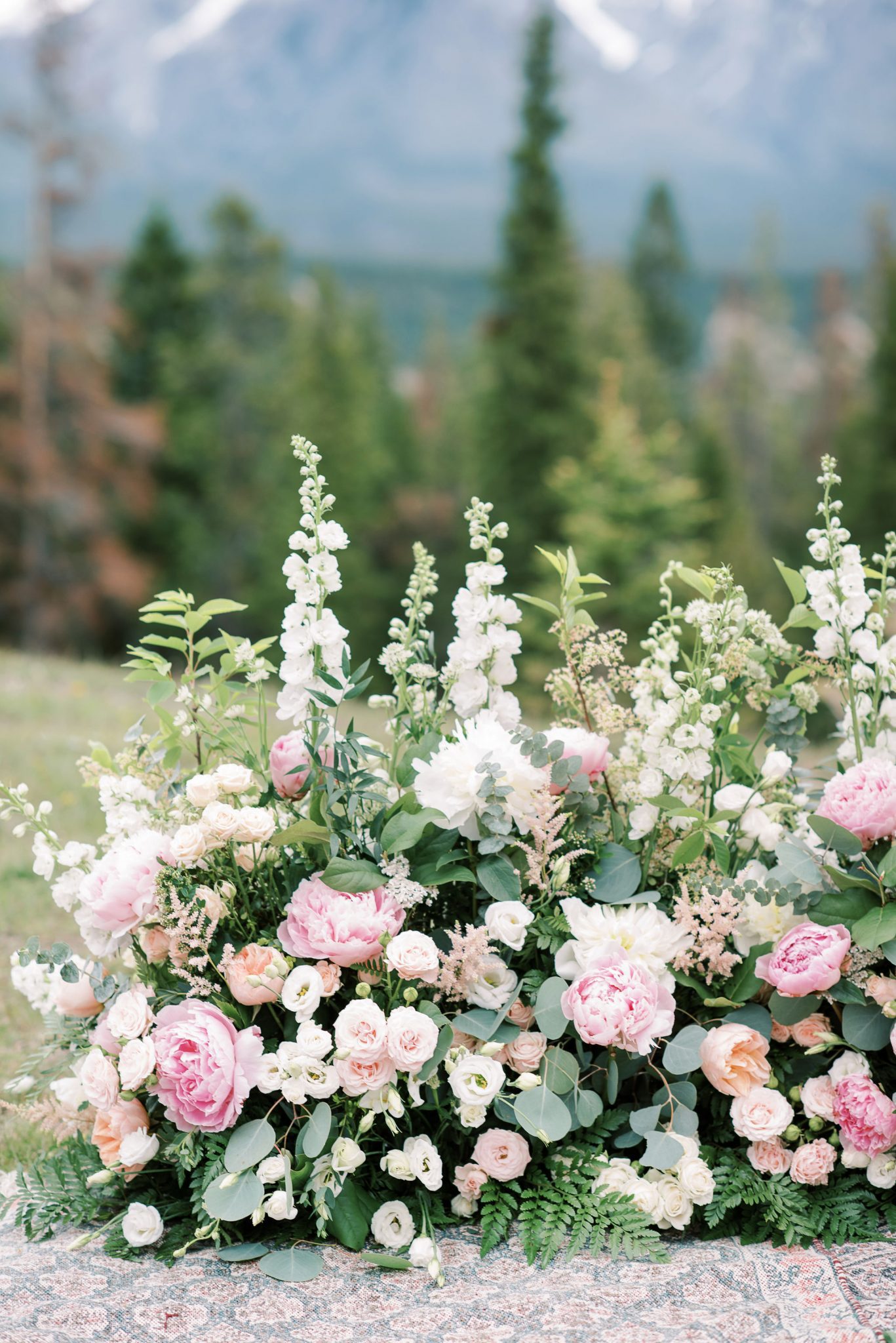 Grounded floral arch featuring white and pink blooms by Flowers by Janie for this Banff National Park elopement