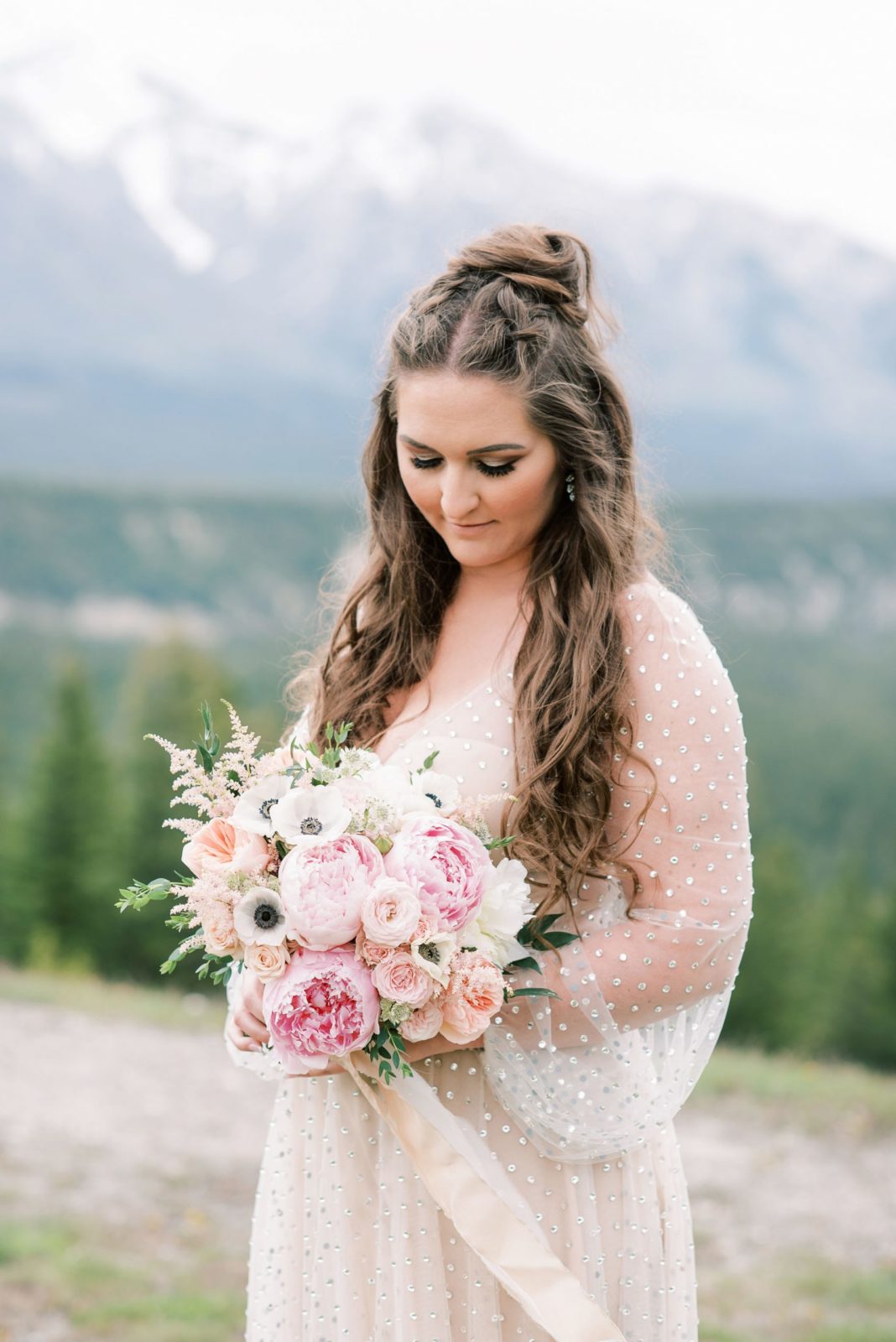 Bride in pearl studded bridal dress by Willowby by Watters holds a blush wedding bouquet