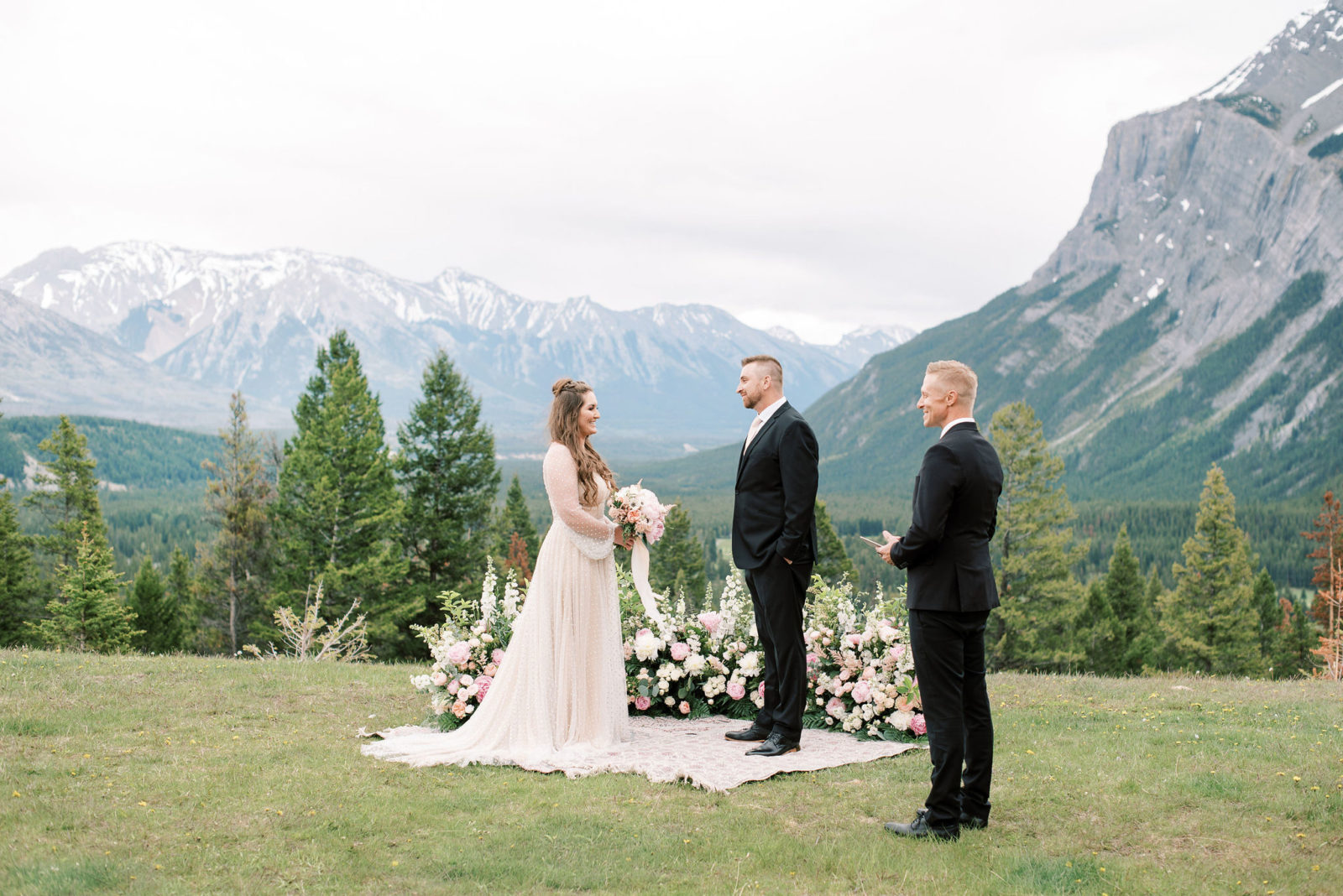 Bride and groom stand in front of a ground floral ceremony arch by Flowers by Janie for their elopement in Banff National Park