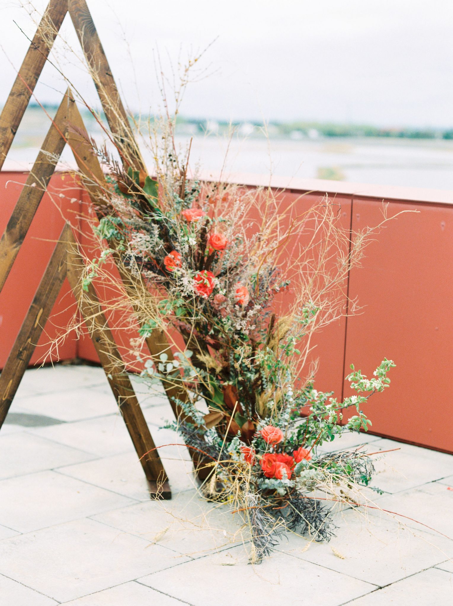 Wooden triangle arches and terracotta flowers as an outdoor wedding ceremony backdrop