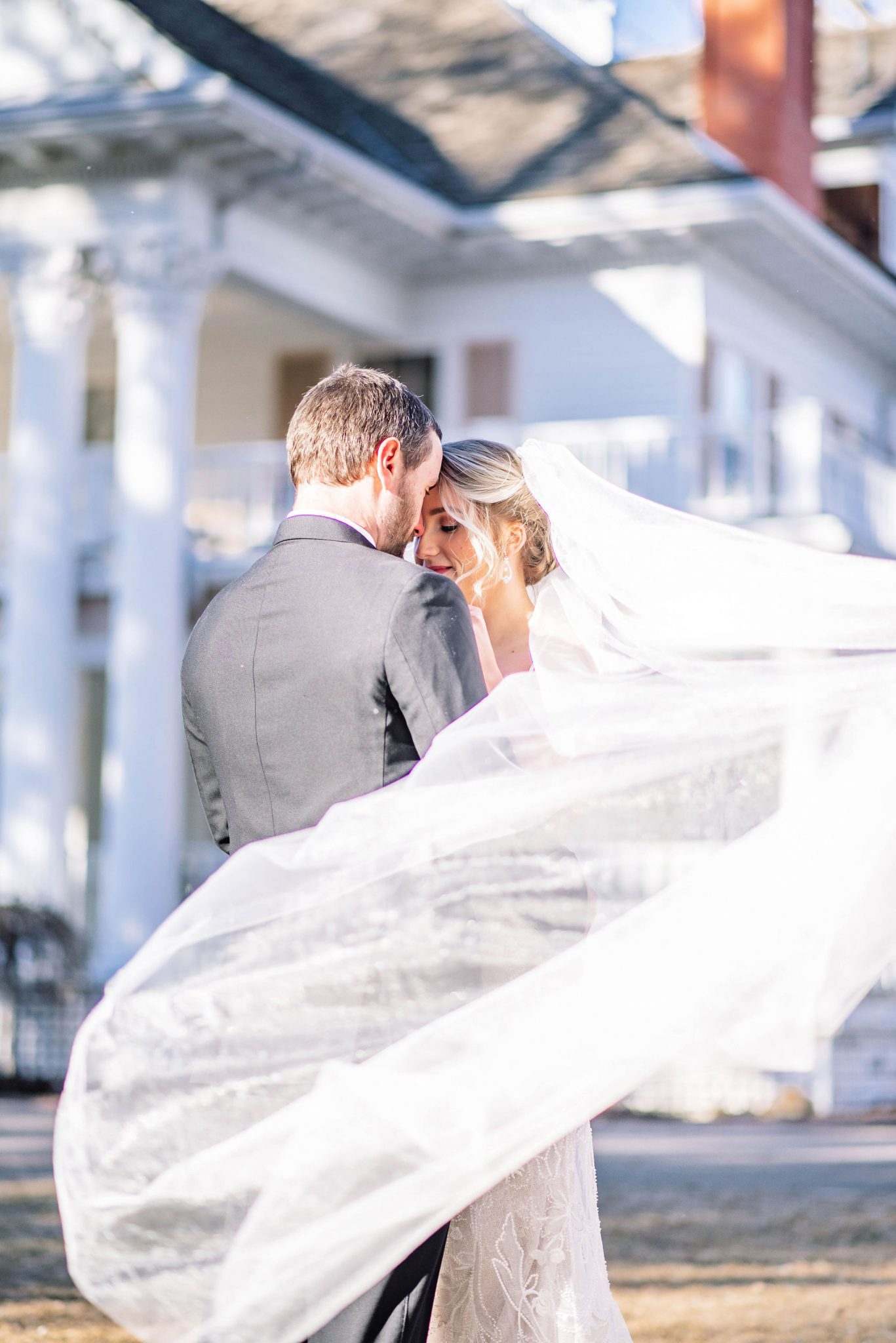Bride's long flowing veil flies in the wind outside the Noralnd Historic Estate Venue