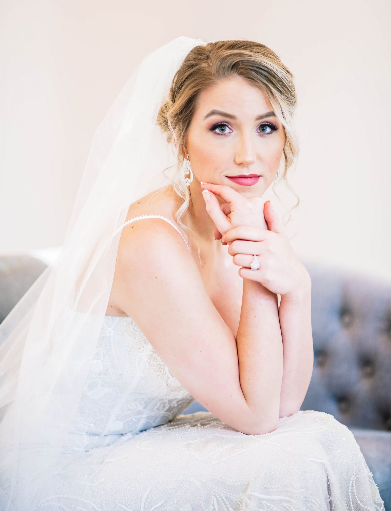 Bride with a romantic updo and veil sits posed for a bridal portrait at the Norland Historic Estate Venue