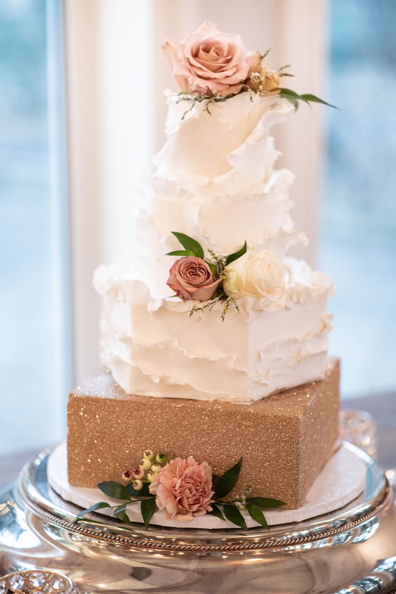 Three tier enchanting wedding cake design with soft white and metallic gold features adorned with pink flowers