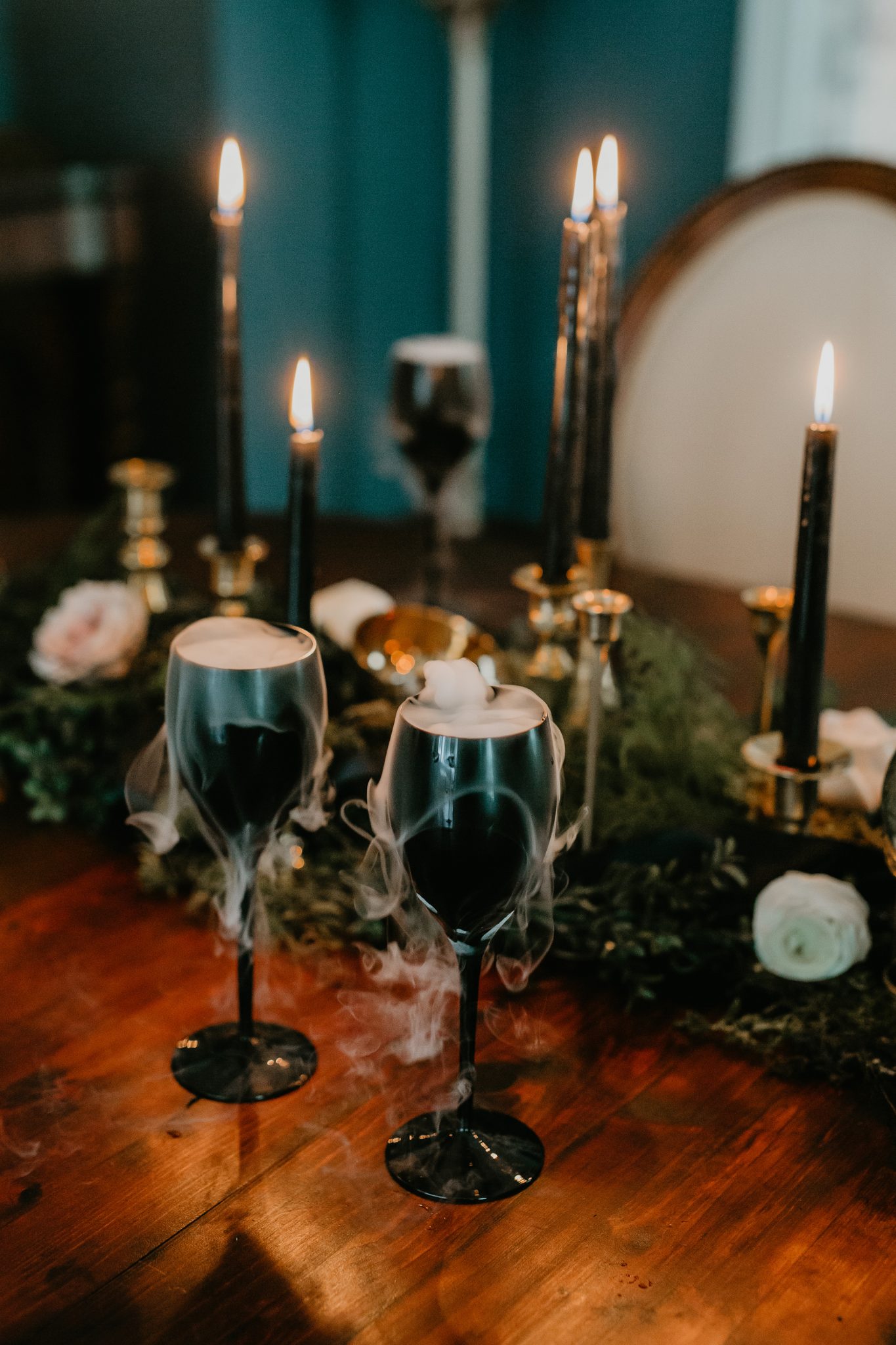 Wine glasses with dry ice on a moody October tablescape with black candles