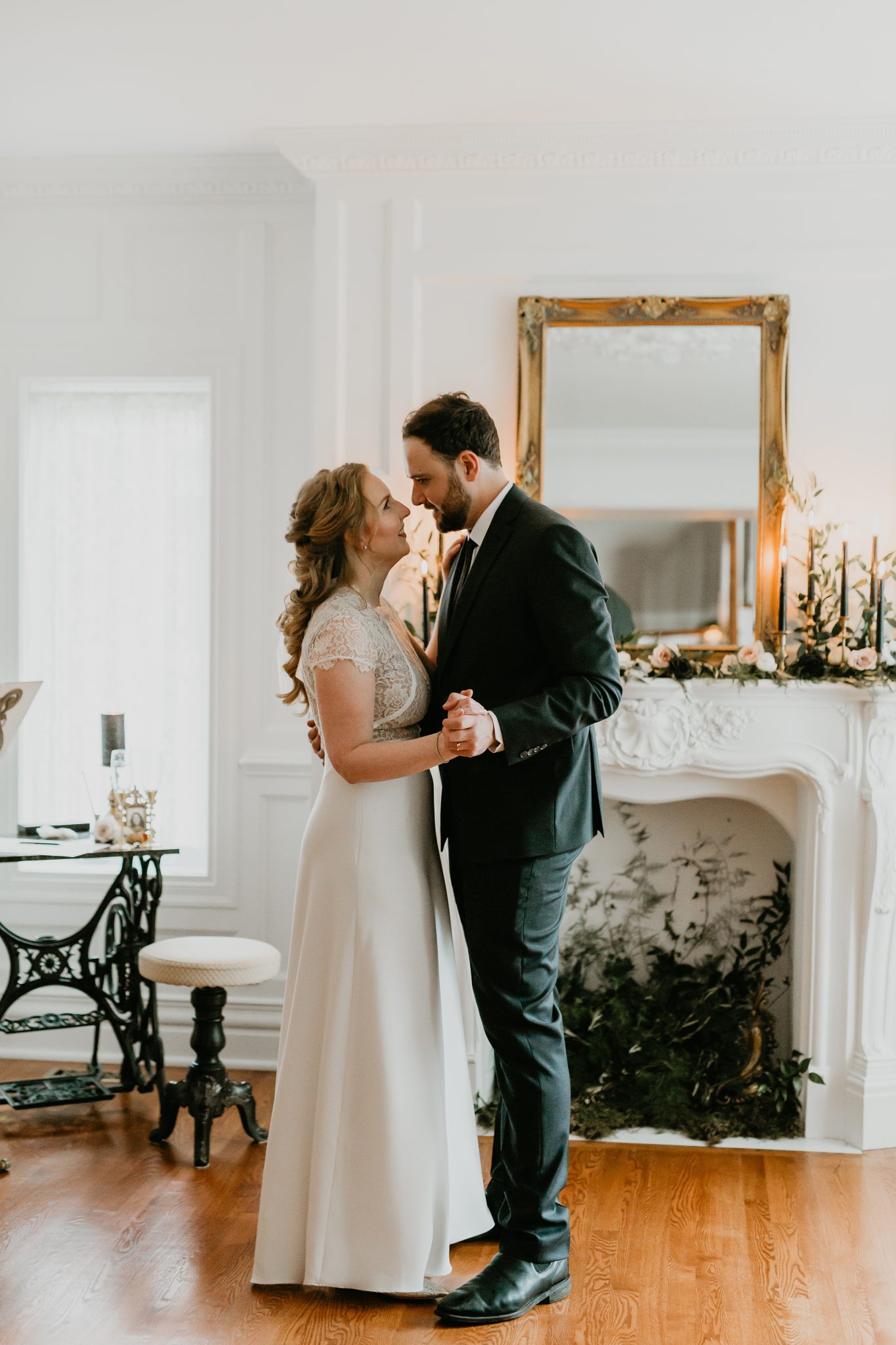 Bride and groom share a first dance in front of styled fireplace for their living room minimony
