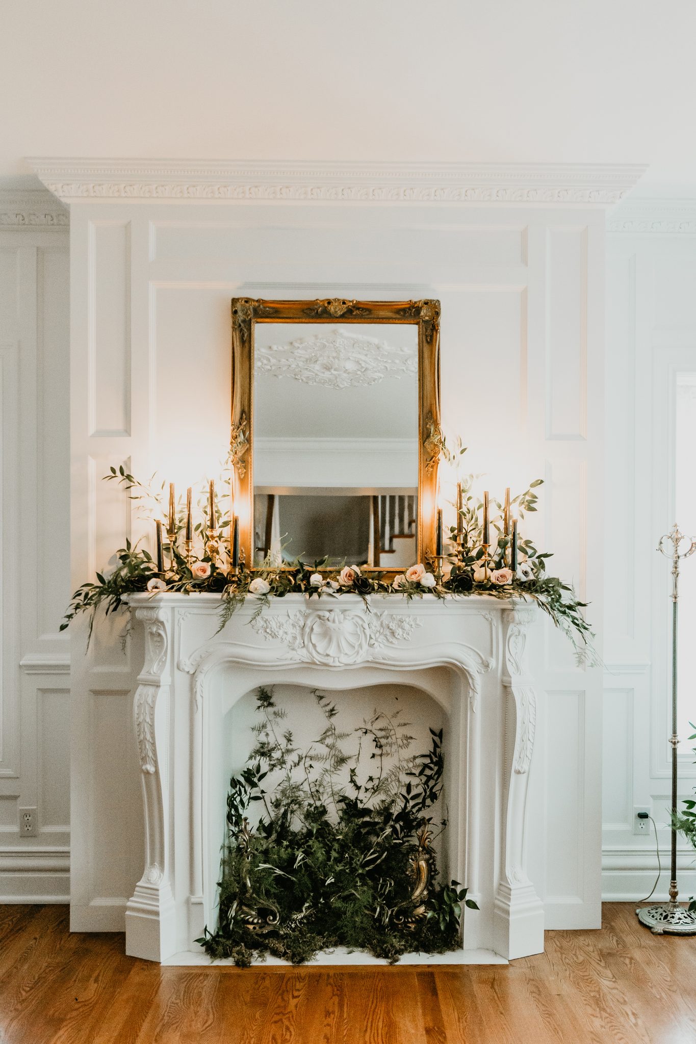 Living room minimony decor inspiration for a vintage styled wedding with greenery in a white fireplace and candles