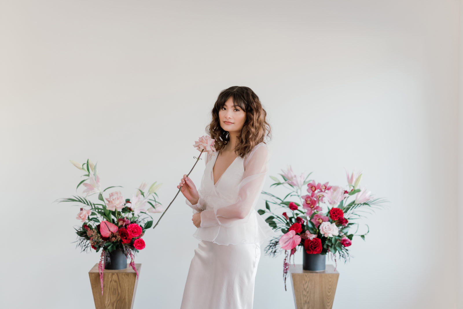 Bride in a gown from Park & Fifth poses in front of a modern microwedding floral display