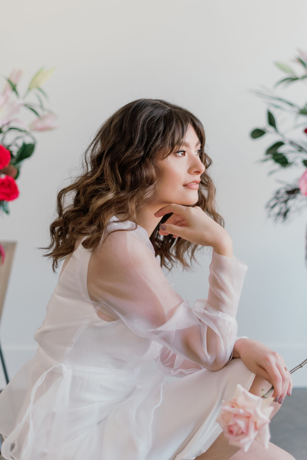 Bride with soft wavy hair and a sheer sleeved gown poses in this modern microwedding inspiration editorial